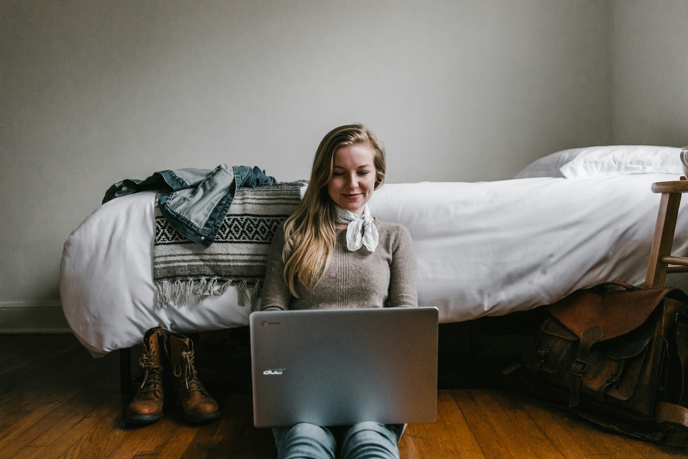 Una mujer sentada junto a su cama mientras usa una computadora portátil | Fuente: Unsplash