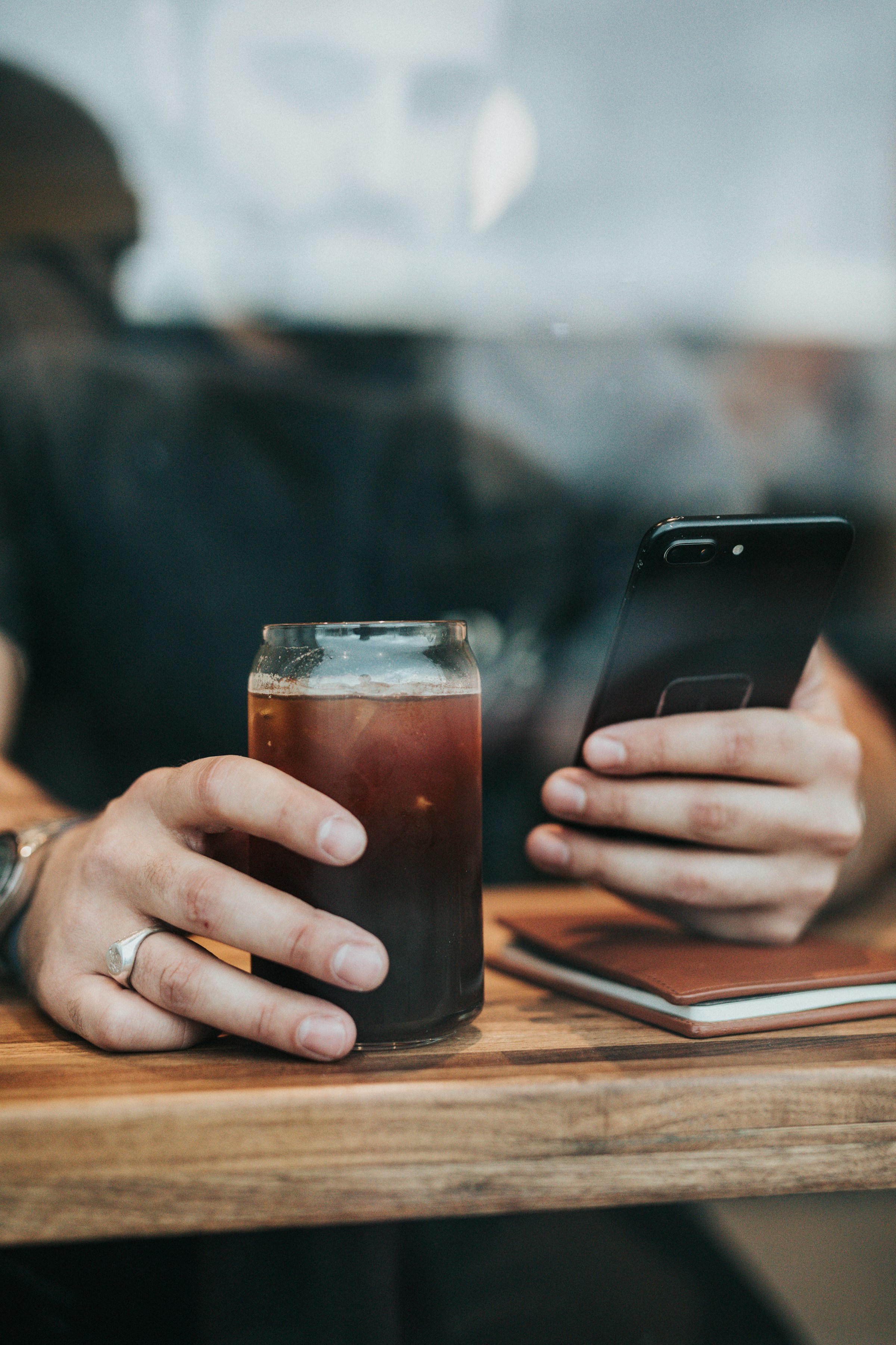 A man using his phone while holding a glass of drink | Source: Unsplash