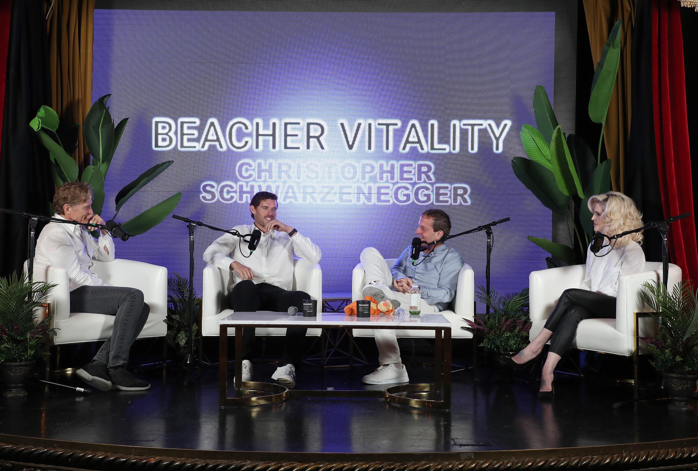 Christopher Schwarzenegger listens intently while exchanging thoughts with Jeff Beacher and Dr. Robert Huizenga during a panel session. His poised body language and sharp appearance reflect the focus and confidence gained throughout his health journey.