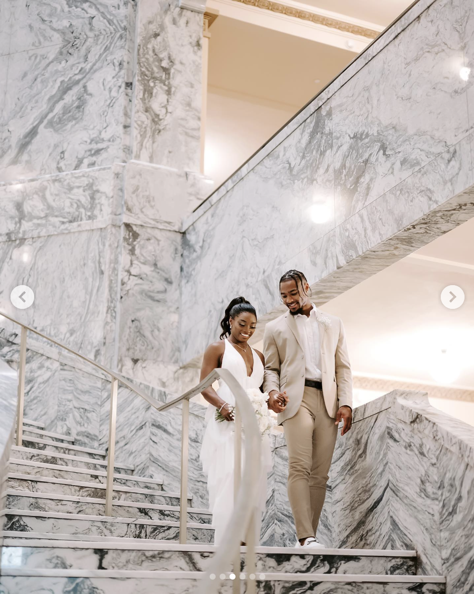 Jonathan Owens and Simone Biles walking hand in hand down a marble staircase on their wedding day, as seen in a post dated April 22, 2023 | Source: Instagram/simonebiles