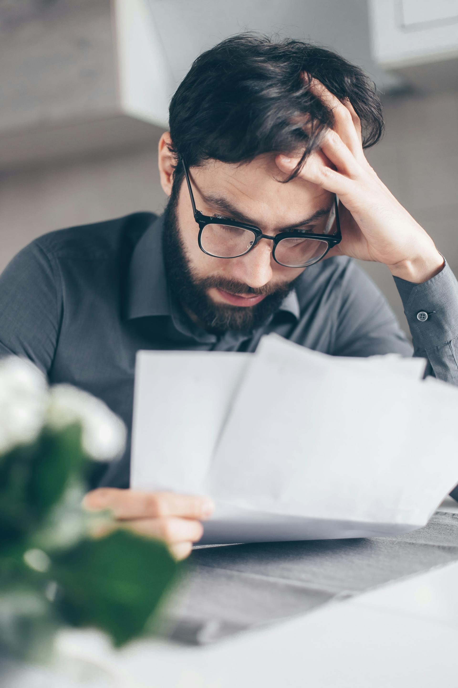 A man looking disturbed while reading the documents in his hand | Source: Pexels