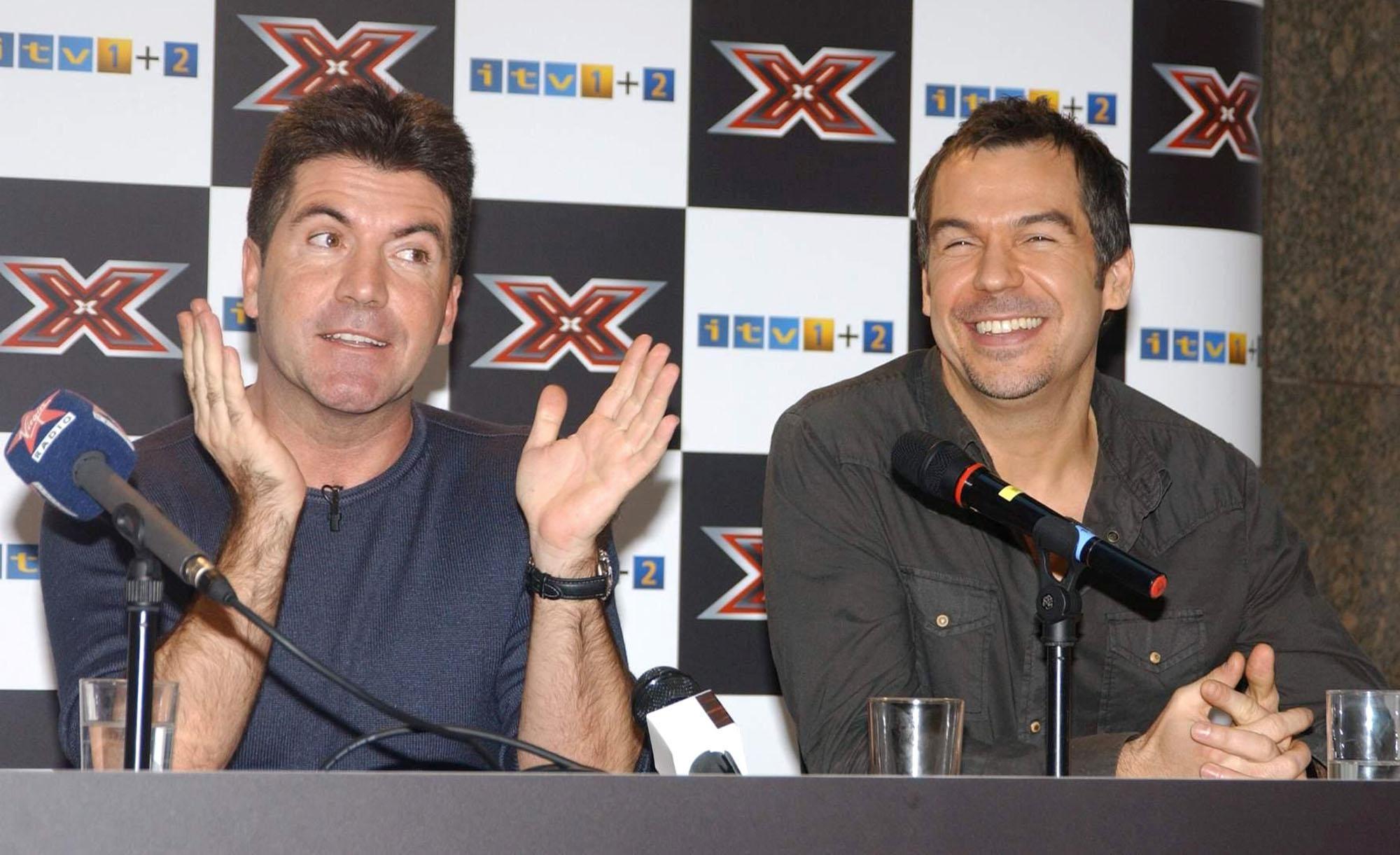 A seemingly relaxed Brookstein shares a laugh with Simon Cowell at a press conference in London on 9 December 2004, the two seated side by side in front of an "X Factor" branded backdrop — the relationship between mentor and winner would sour dramatically within months.