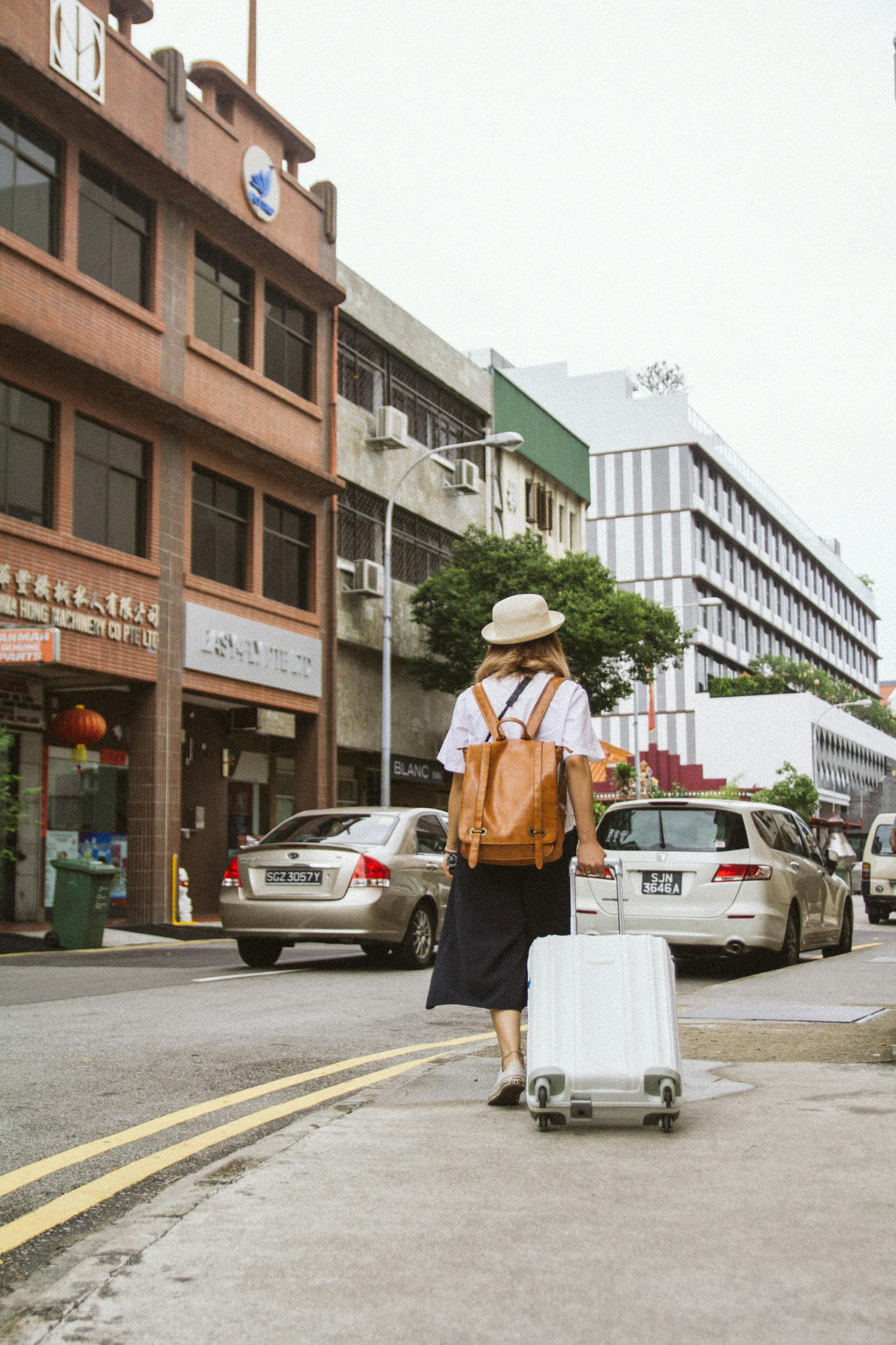 Young woman wheeling a suitcase | Source: Pexels
