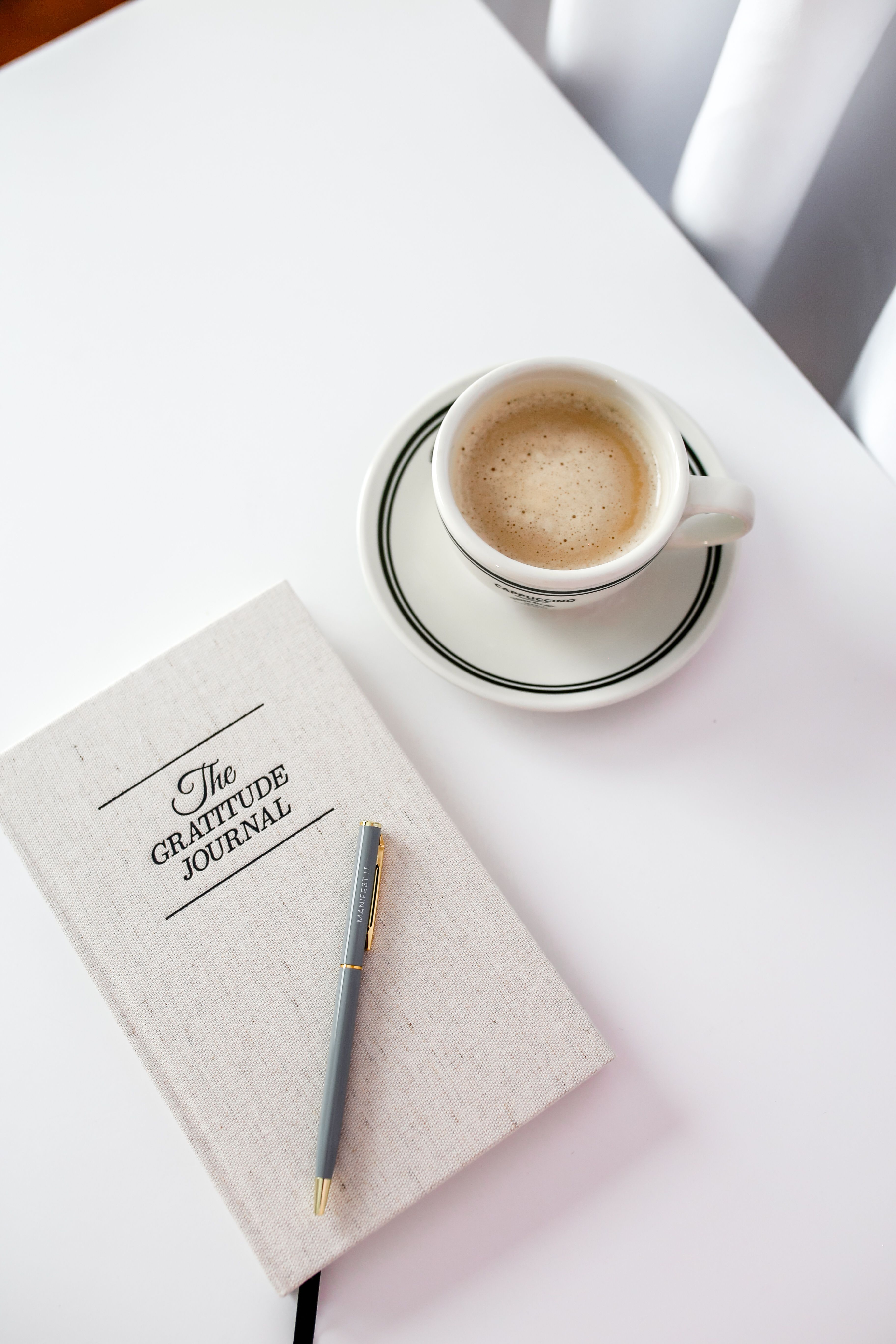 A gratitude journal beside a cup of coffee | Source: Pexels