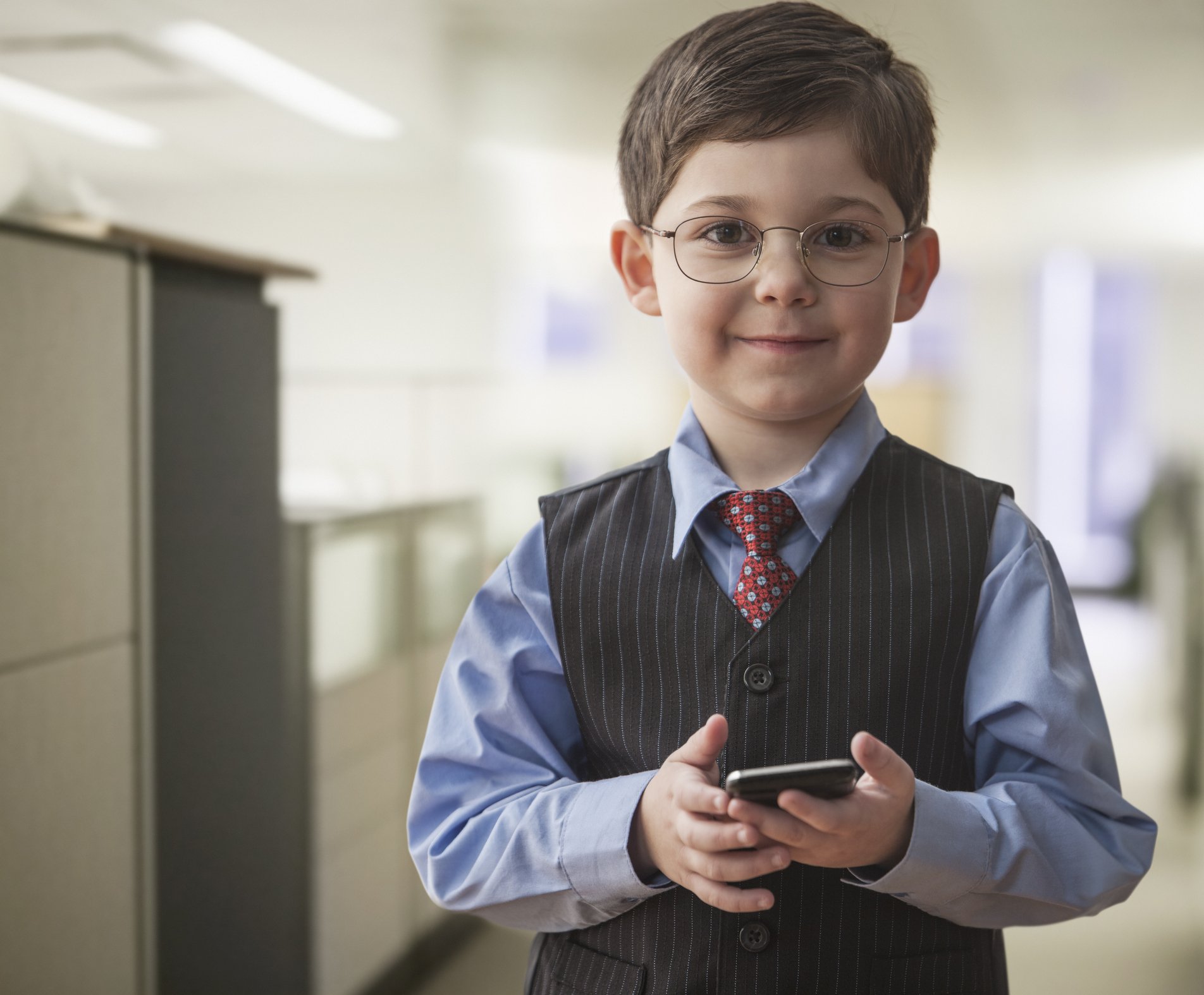 Photo of boy wearing businessman outfit in office | Photo: Getty Images