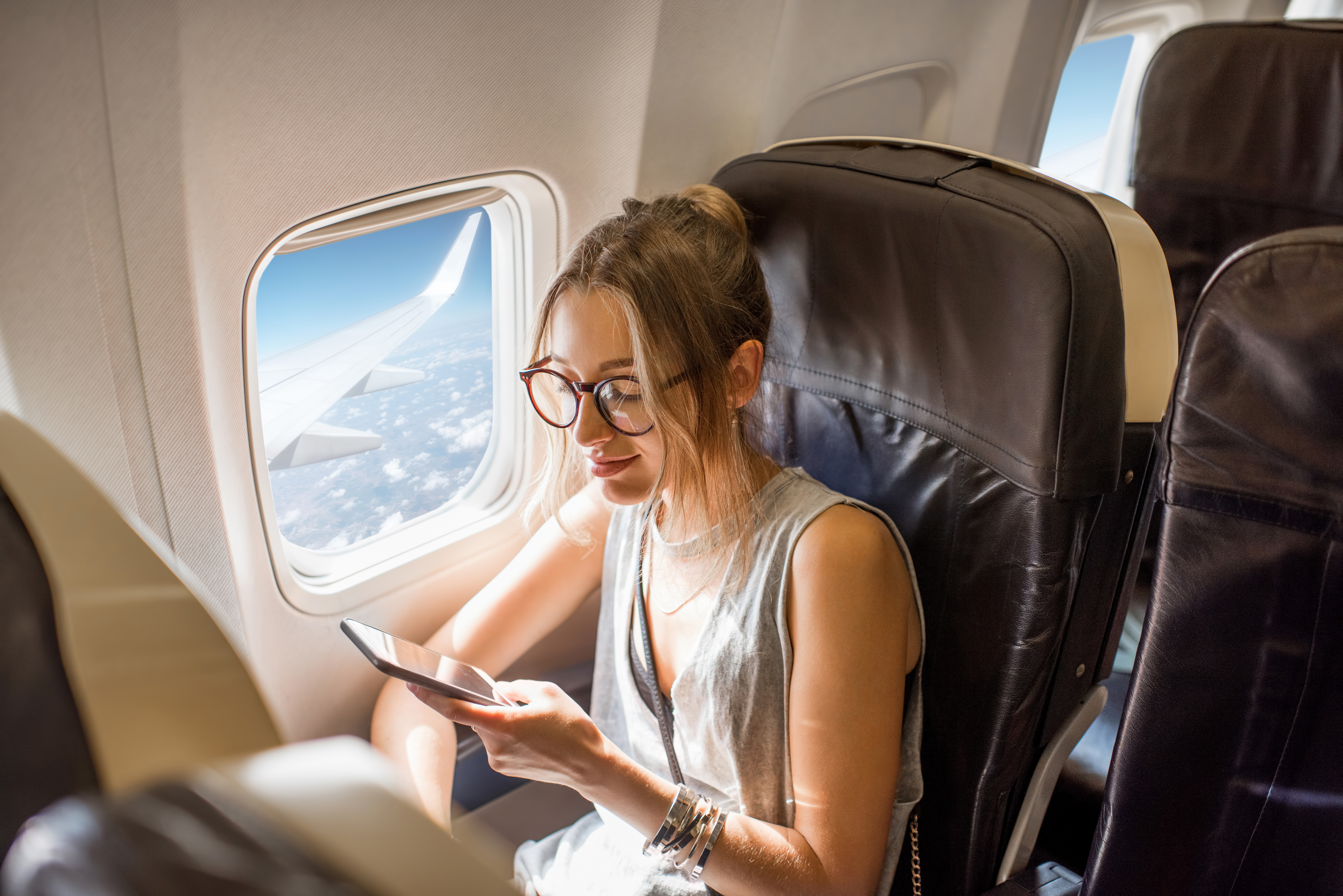 A young woman holding her phone mid-flight | Source: Shutterstock