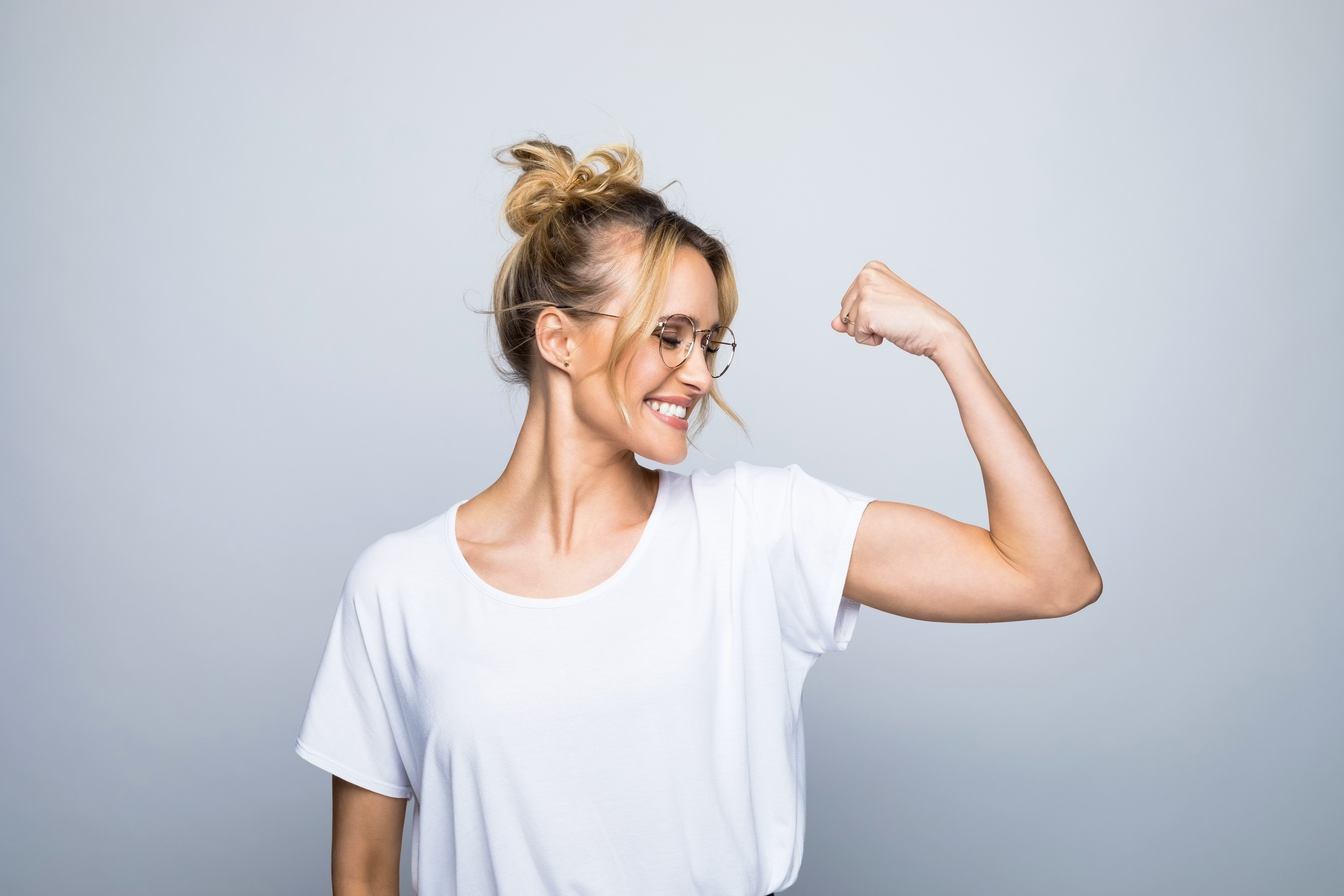 Happy beautiful woman flexing muscle | Source: Getty Images