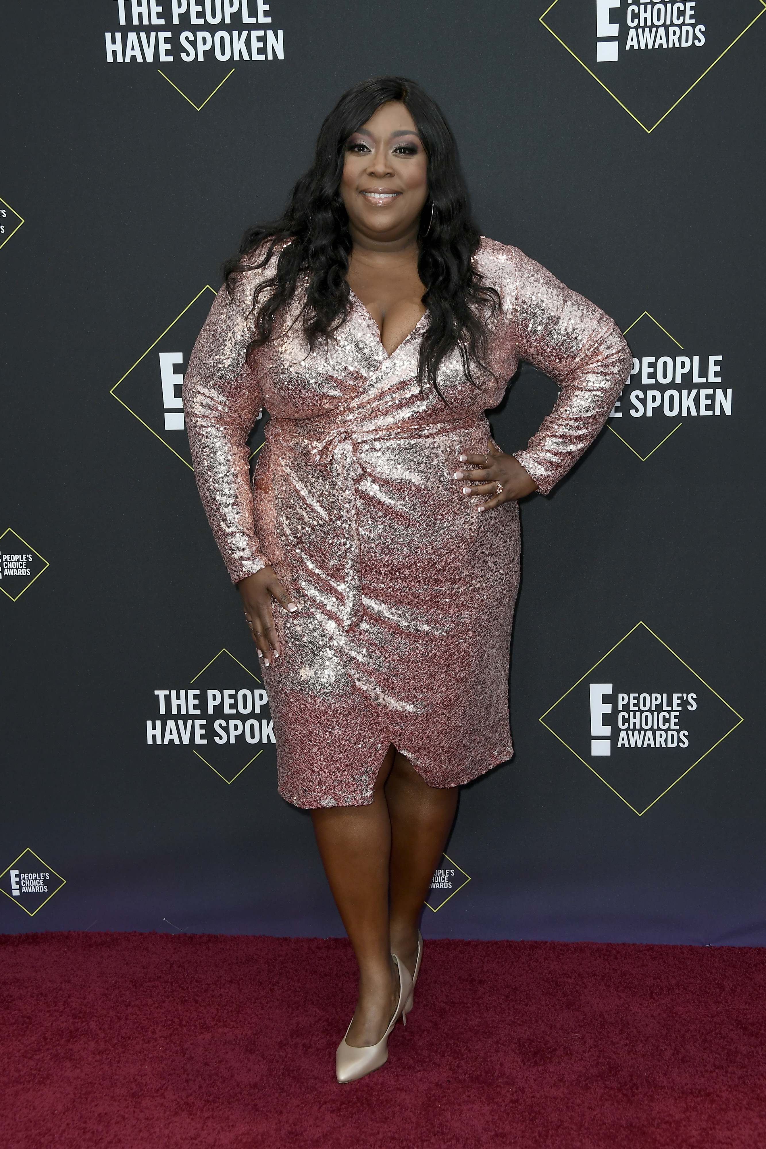 Loni Love arrives at the E! People's Choice Awards on November 10, shining in a rose-gold sequined dress, nude heels, and soft waves as she poses on the red carpet.