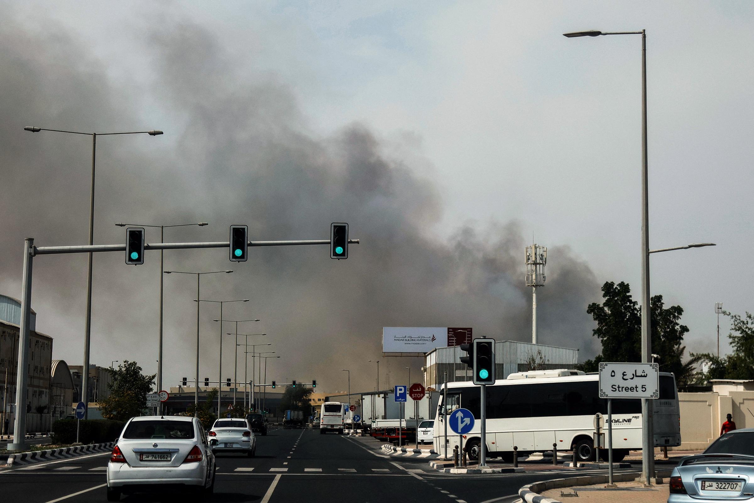 Motorists drive past a plume of smoke rising from a reported Iranian strike in the industrial district of Doha on 1 March 2026. | Source: Getty Images