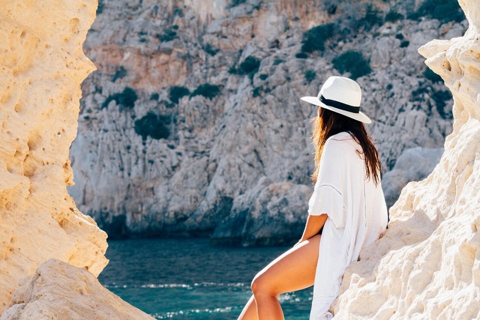 Une jeune femme qui saute à la plage, un chapeau à la main | Photo : Pexels