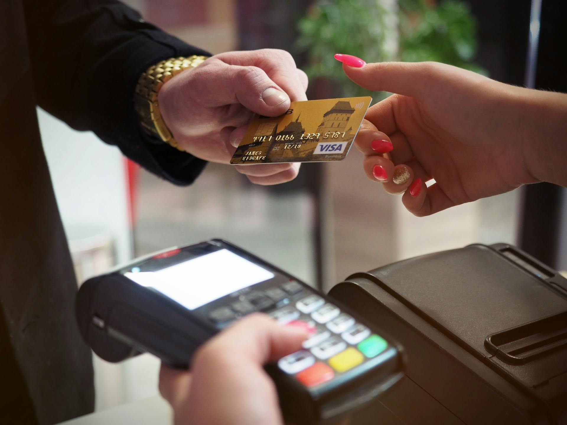 A man handing his card to a cashier woman to swipe it for payment | Source: Pexels