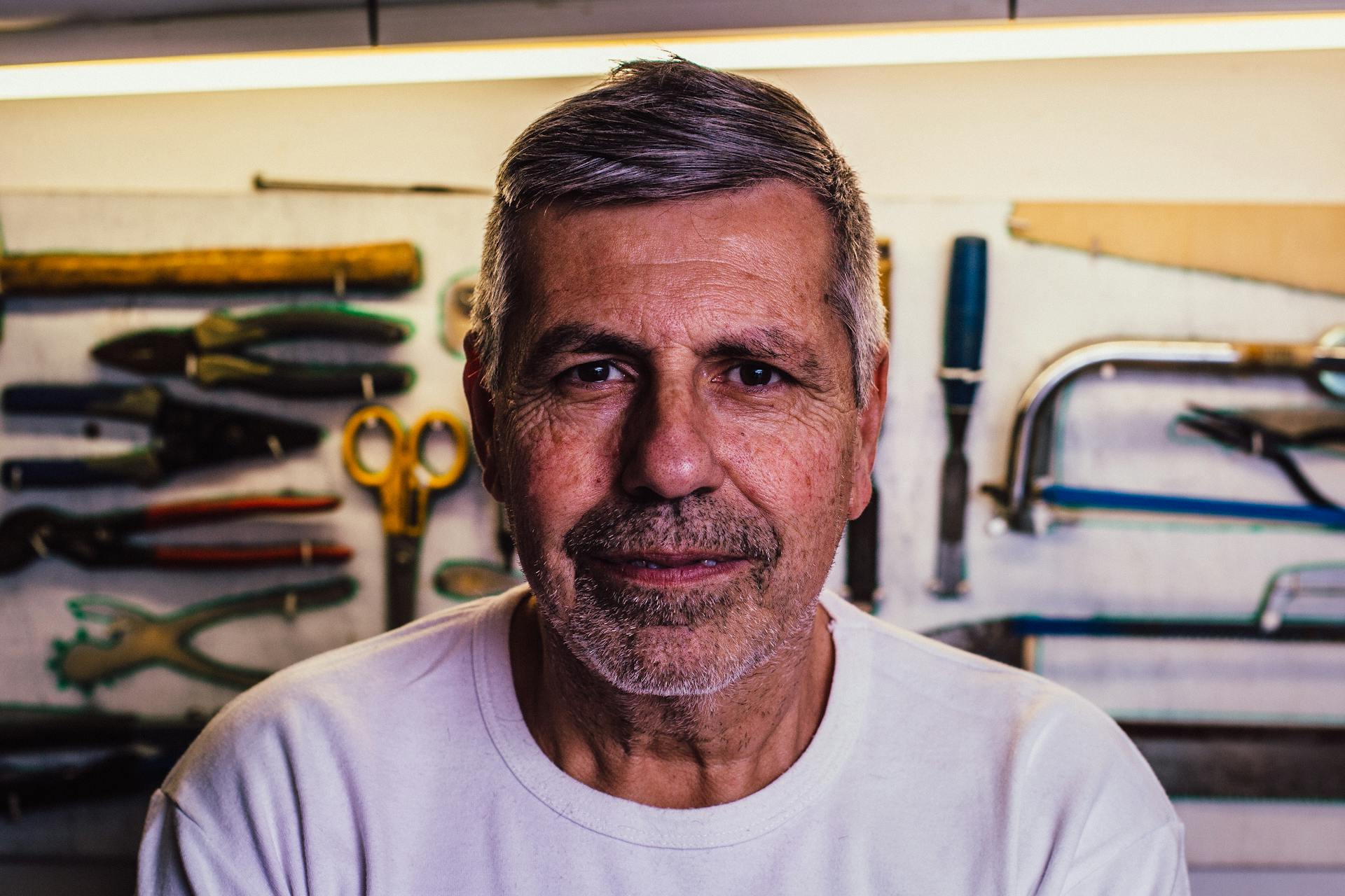 An elderly man with assorted hand tools in the background | Source: Pexels