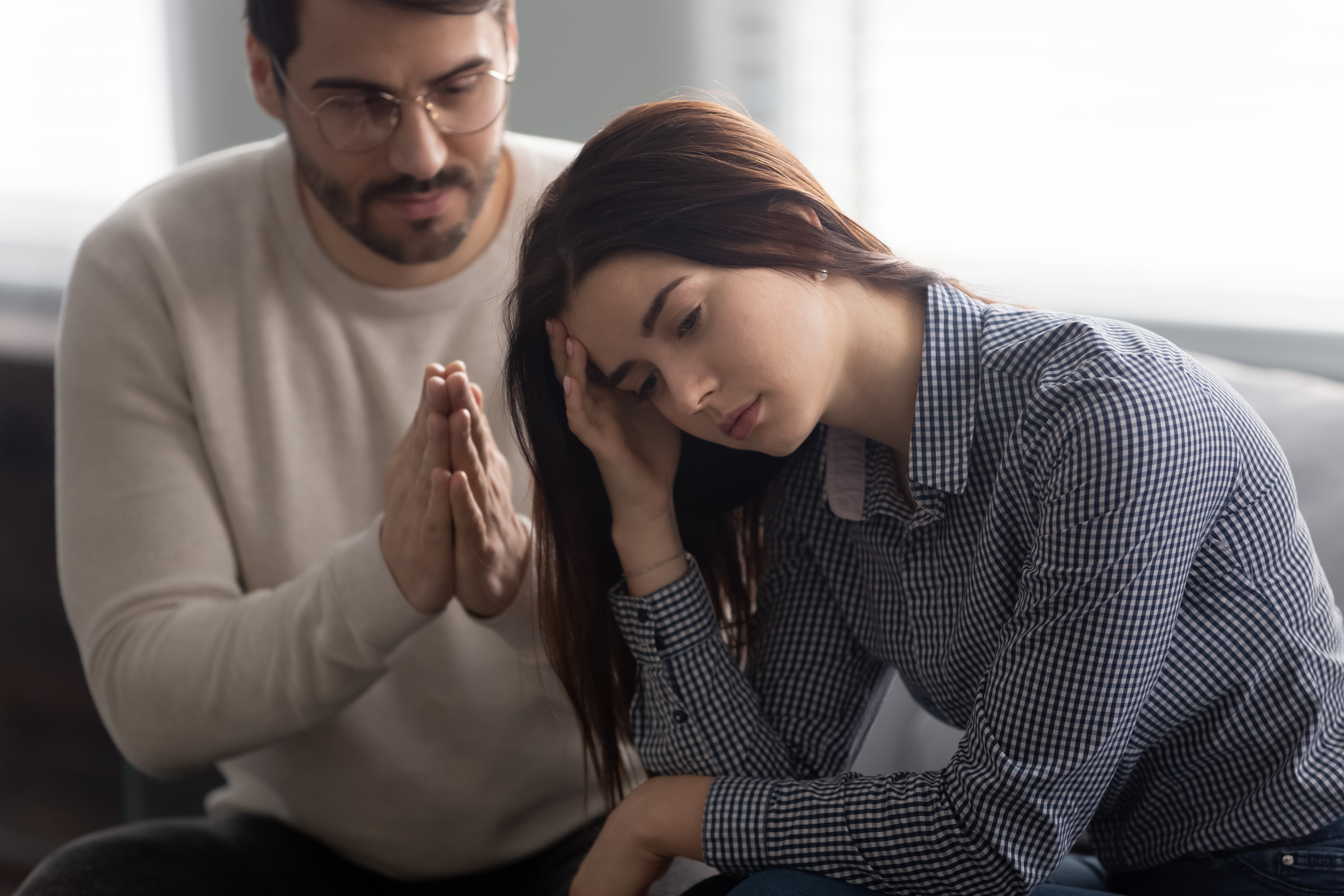 A man apologizing while a woman looks disheartened | Source: Shutterstock