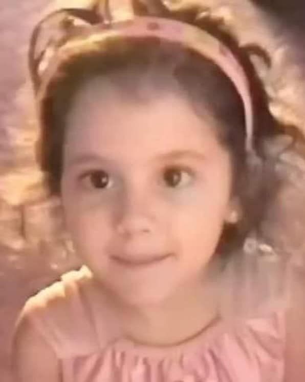 Little Ariana Grande in a pink dress and matching headband, softly lit and full of gentle curiosity | Source: Facebook/arianagrande