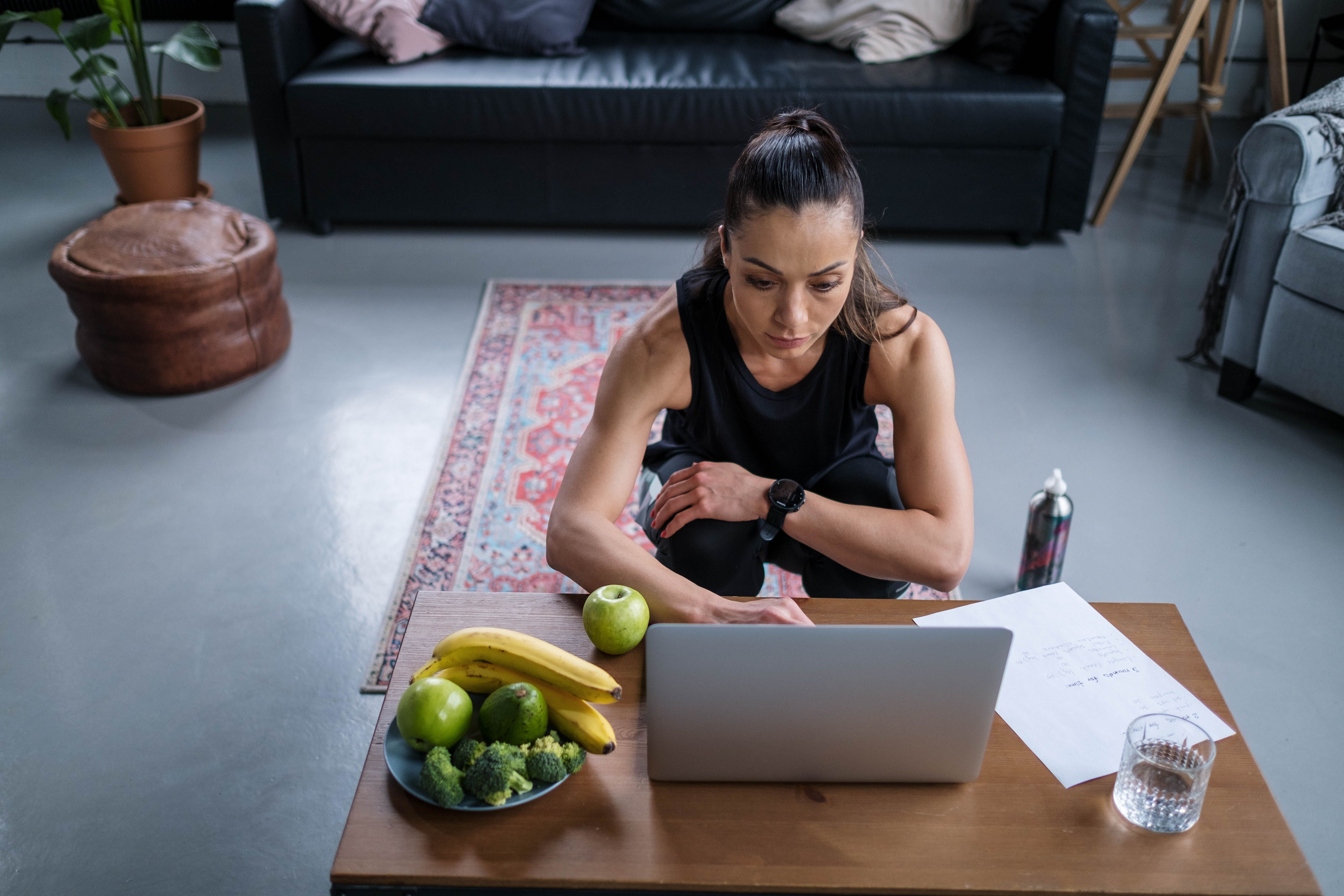 A woman in workout clothes uses a laptop after exercising at home. | Source: Pexels