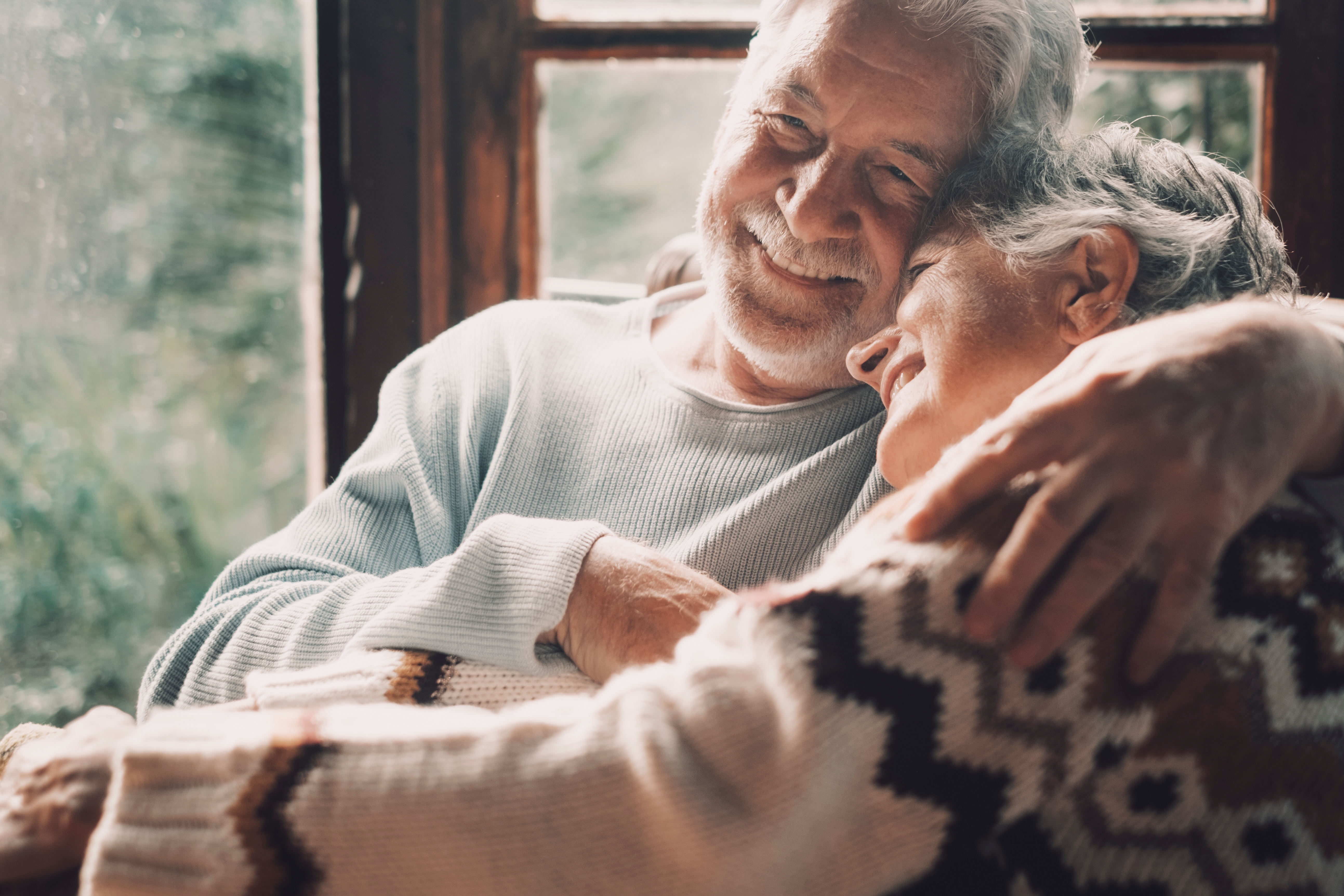 Old senior couple in love hug and embrace with romance together at home. | Source: Shutterstock