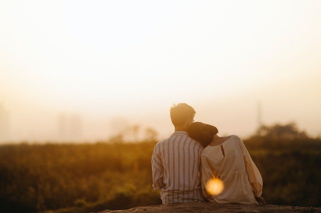 Ein Paar sitzt dicht nebeneinander und blickt dem Sonnenuntergang entgegen | Quelle: Văn Thắng aus Pexels