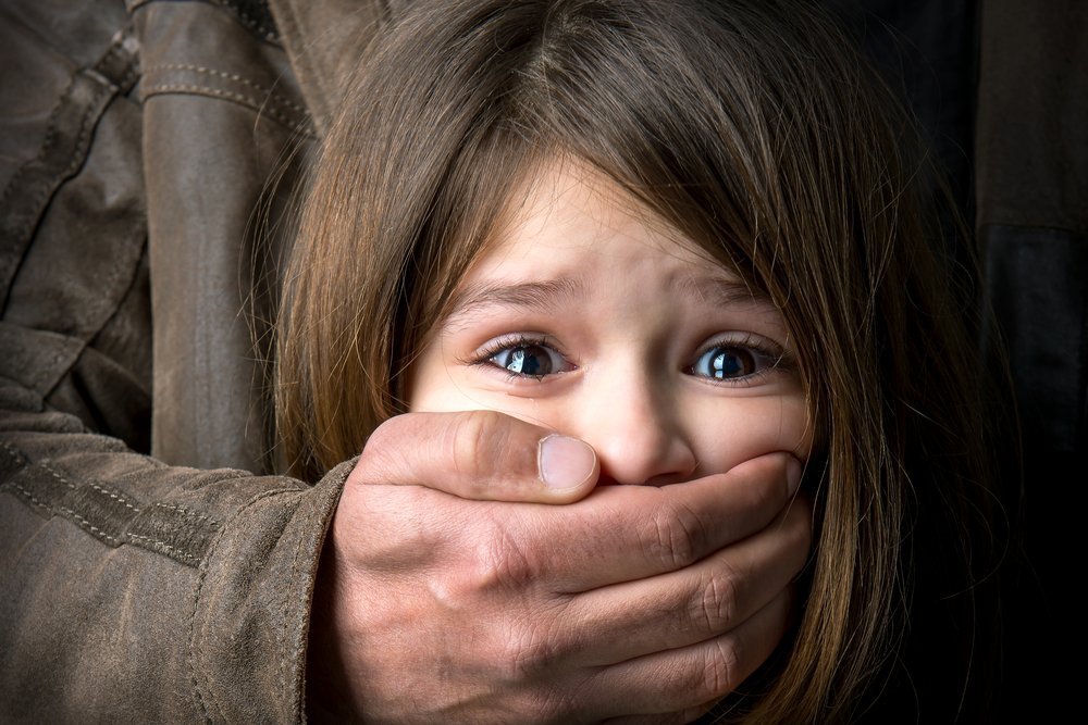 Adult man's hand covering scared young girl's mouth | Photo: Shutterstock