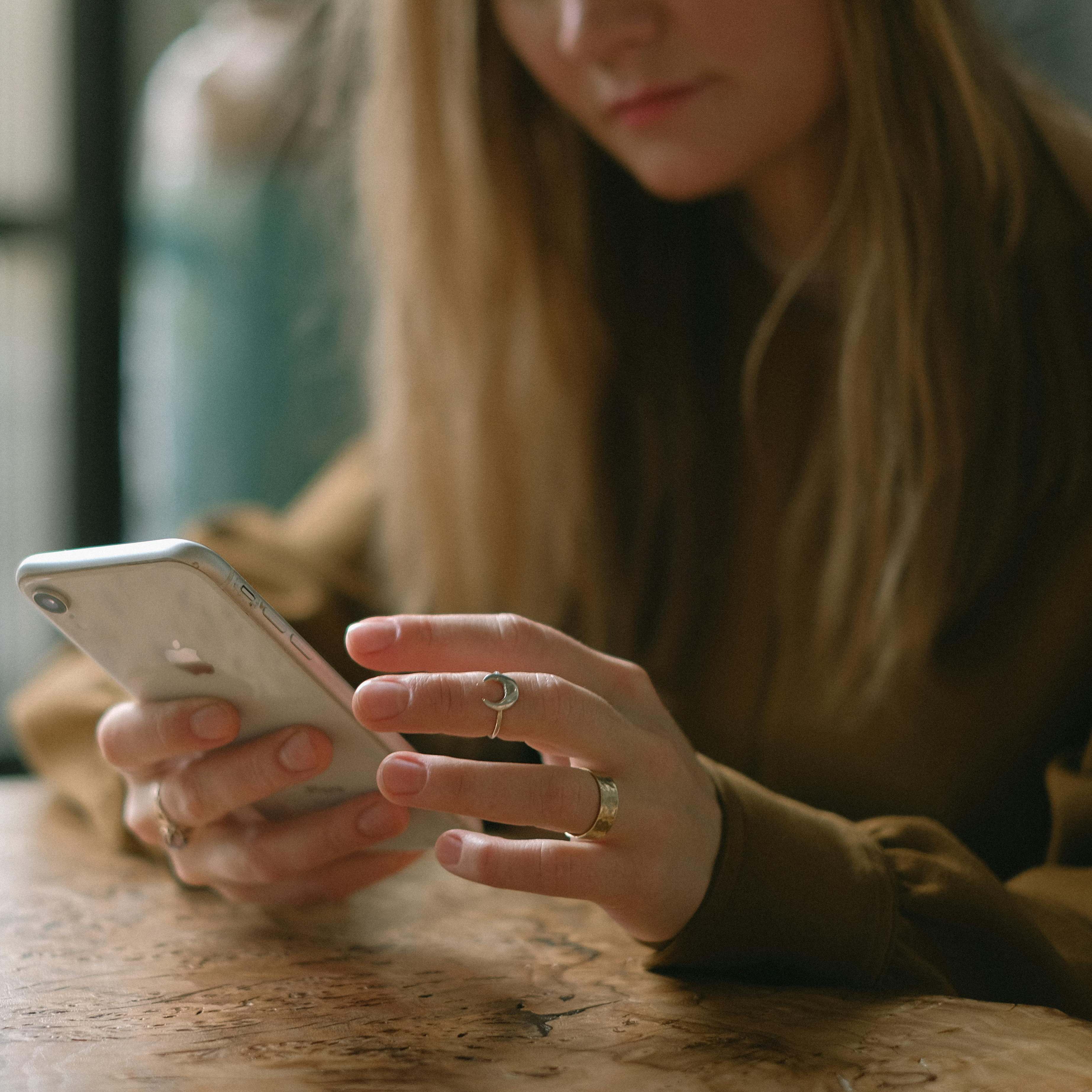 A woman seated at a restaurant table, looking at her phone | Source: Pexels