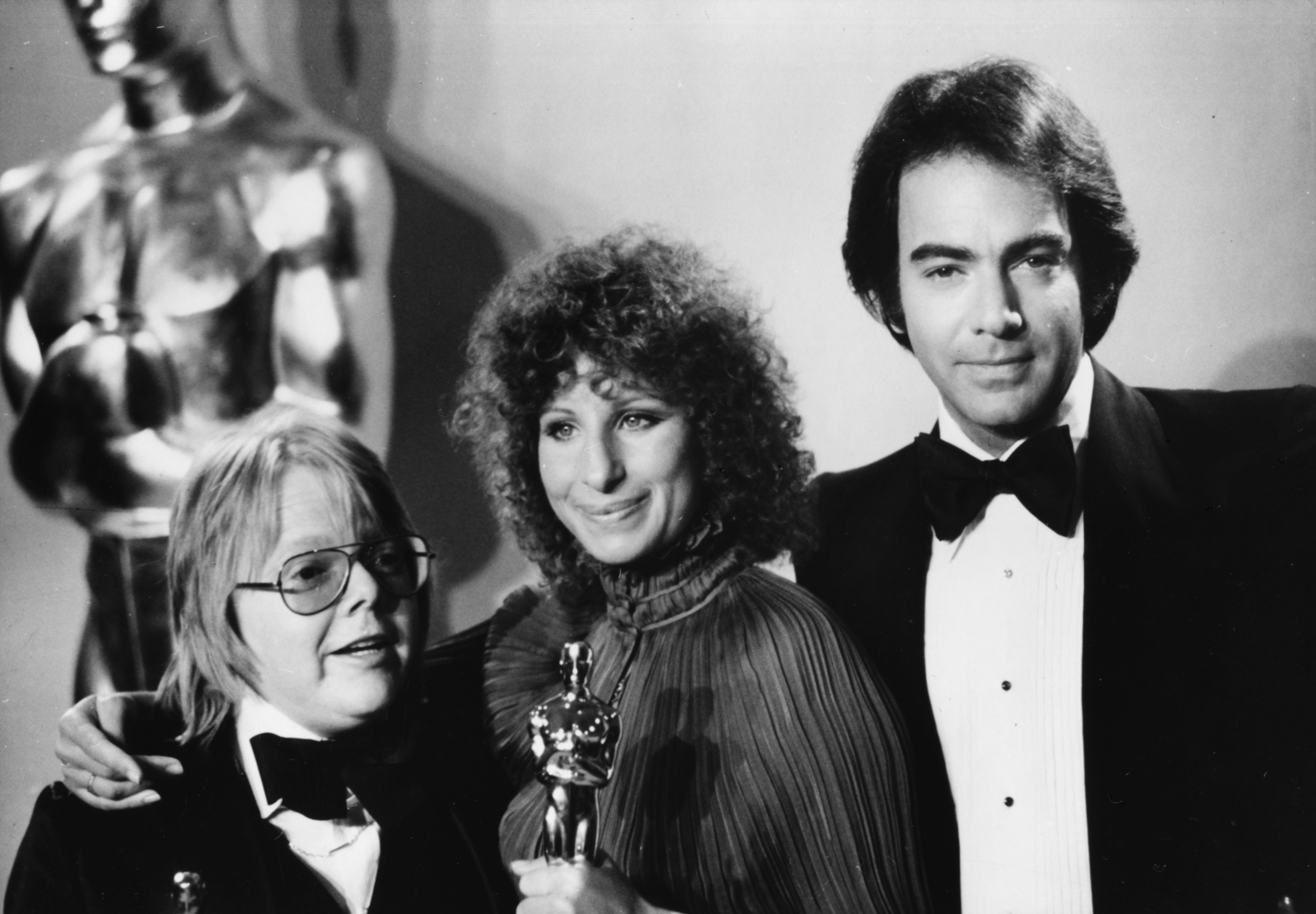 Paul Williams and Barbra Streisand hold their Oscars for Best Original Song alongside the legendary musician who was the presenter for the occasion, on March 28, 1977 | Source: Getty Images
