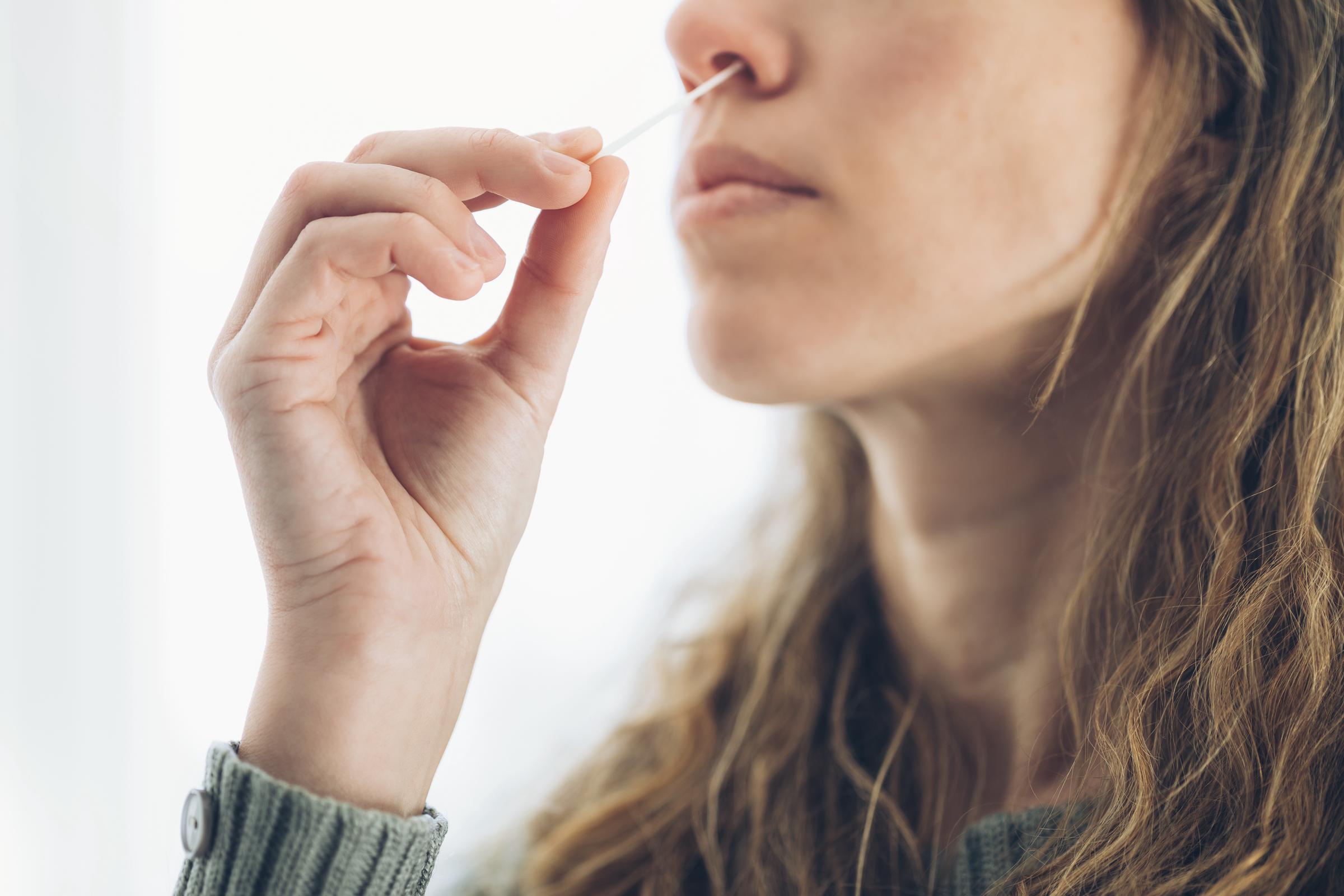 A woman inserting a swab into her nose | Source: Getty Images