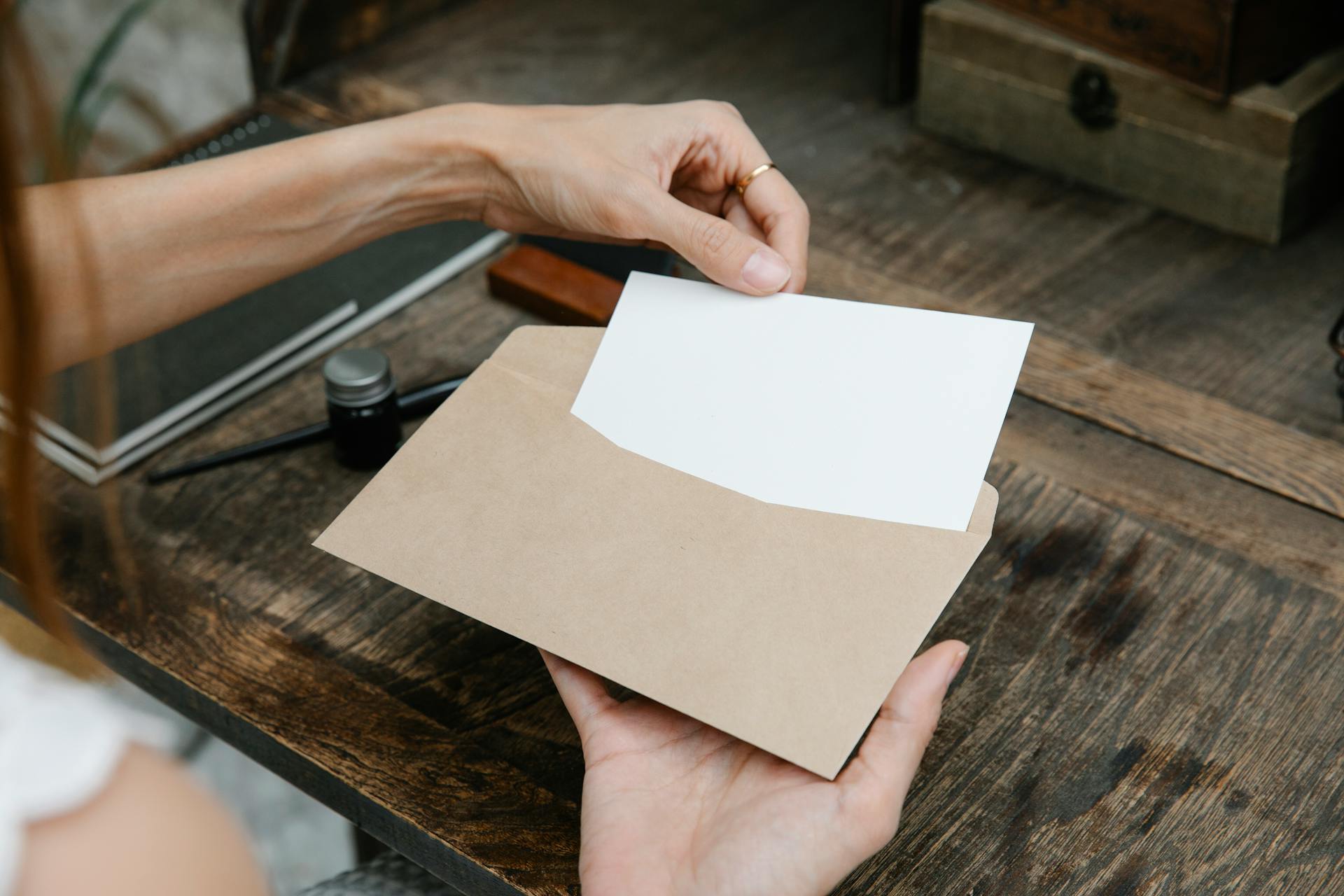 A woman placing a letter in an envelope | Source: Pexels