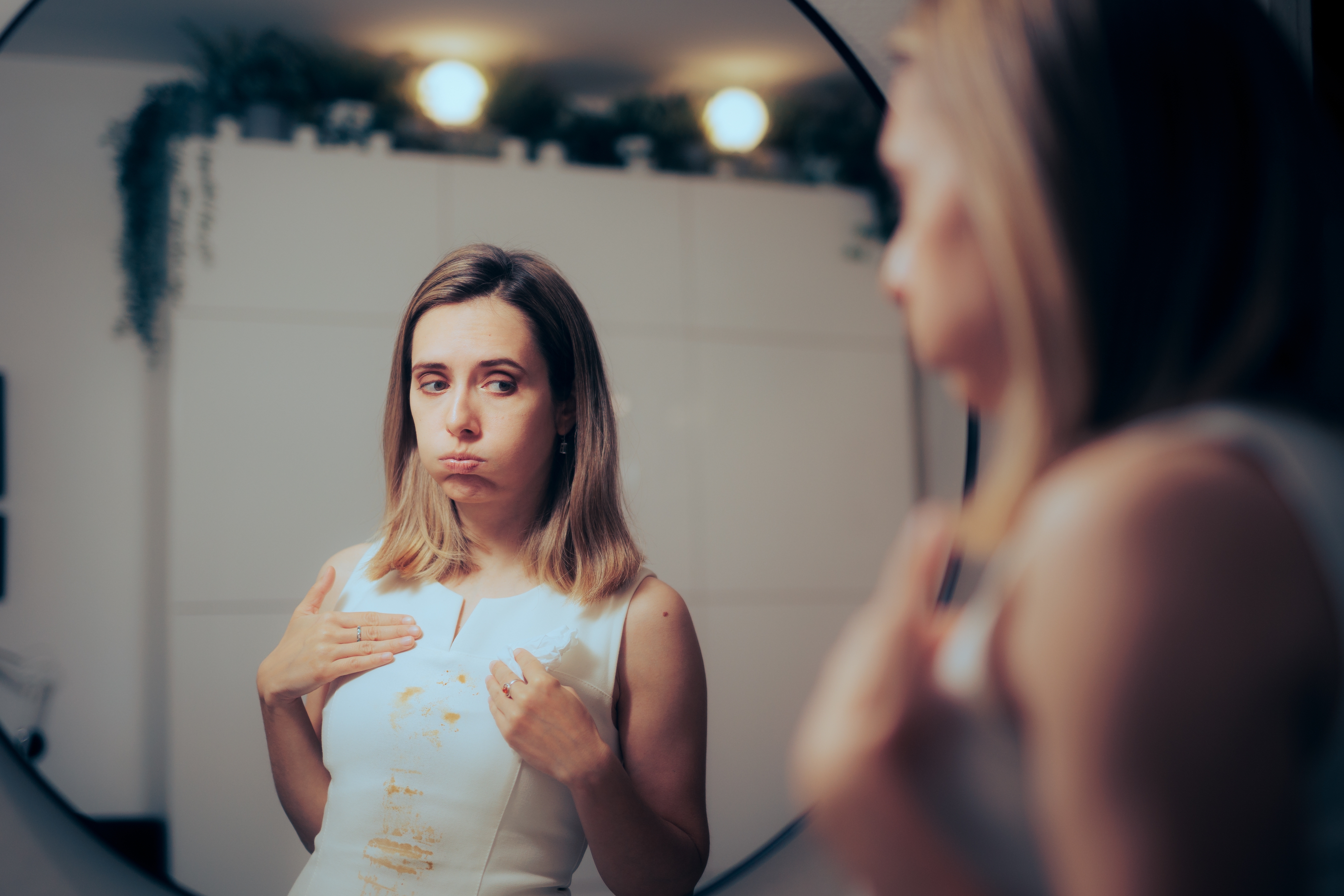A woman looking at herself in the mirror and appearing unhappy | Source: Shutterstock