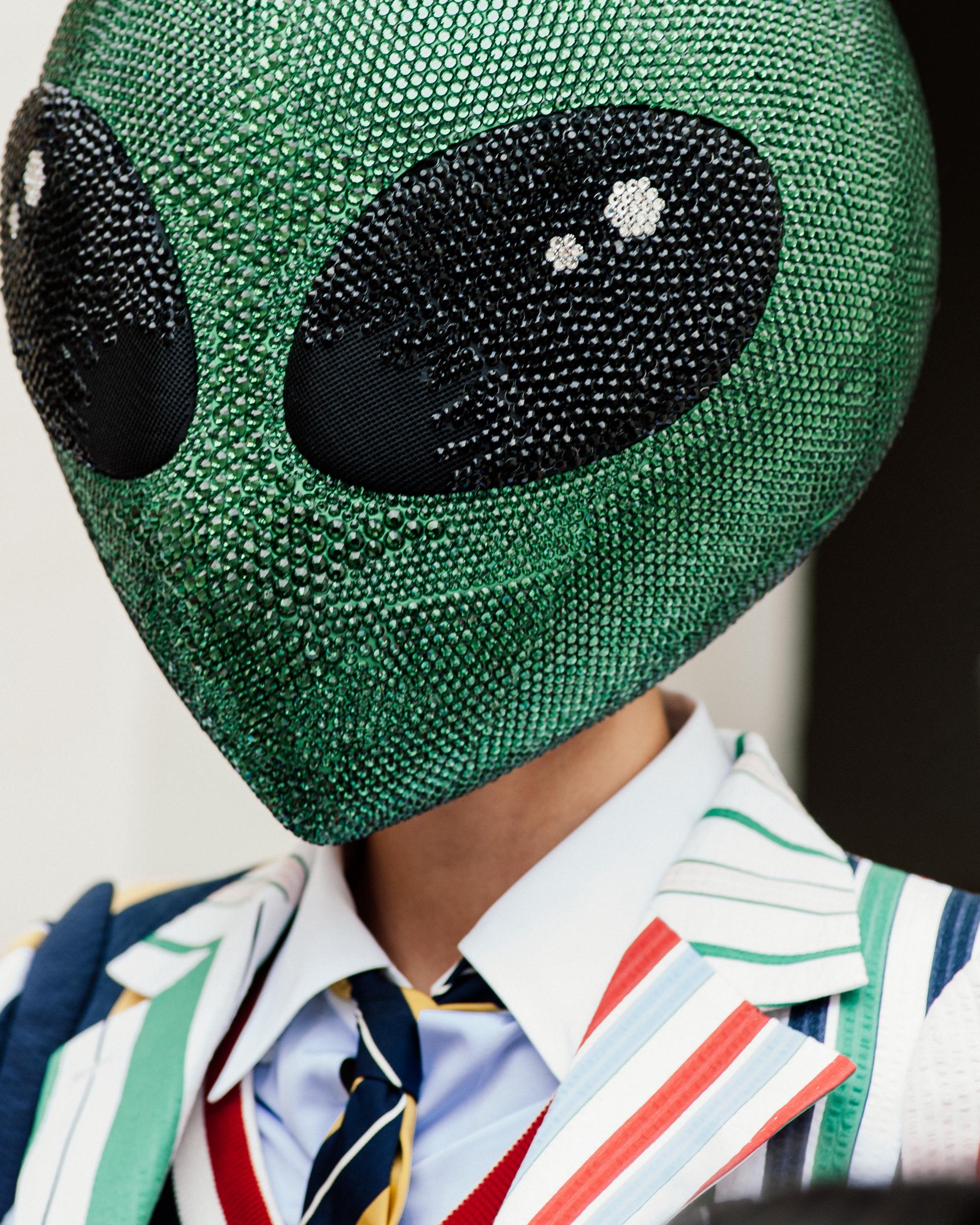 A close-up shot captures the large green alien head with black eyes, evoking a scene straight out of a Marvel alien movie. The look breaks from the usual Paris Fashion Week norms, introducing a bold, cinematic twist to the runway.