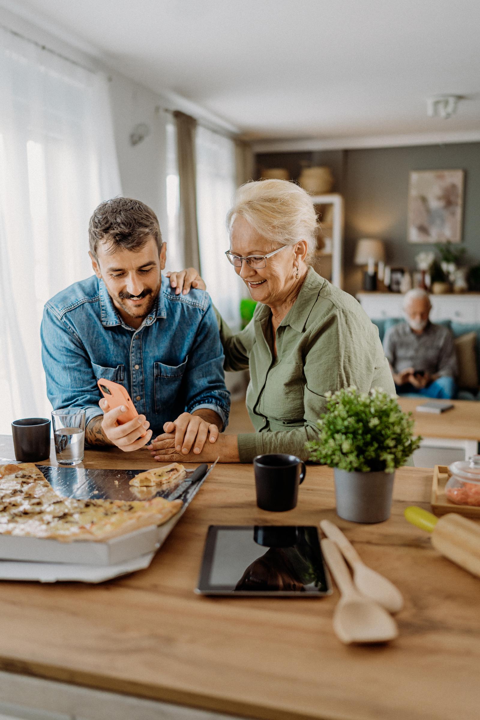 Son teaching his mother how to use a smartphone | Source: Getty Images