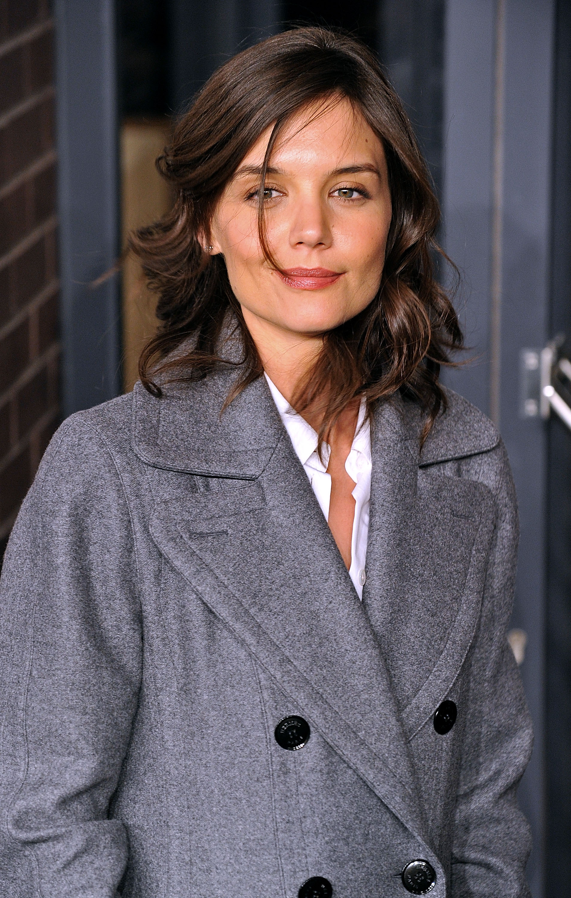 Katie Holmes embraced polished city sophistication in a tailored gray coat layered over crisp white separates. With tousled waves and understated glam, the actress brought effortless Manhattan chic to the upscale fashion event.