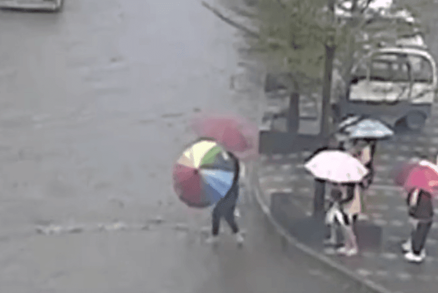 Maestra cargando a sus alumnos sobre una calle inundada en China. | Imagen: YouTube/Daily Mail Maestra cargando a sus alumnos sobre una calle inundada en China. | Imagen: YouTube/Daily Mail
