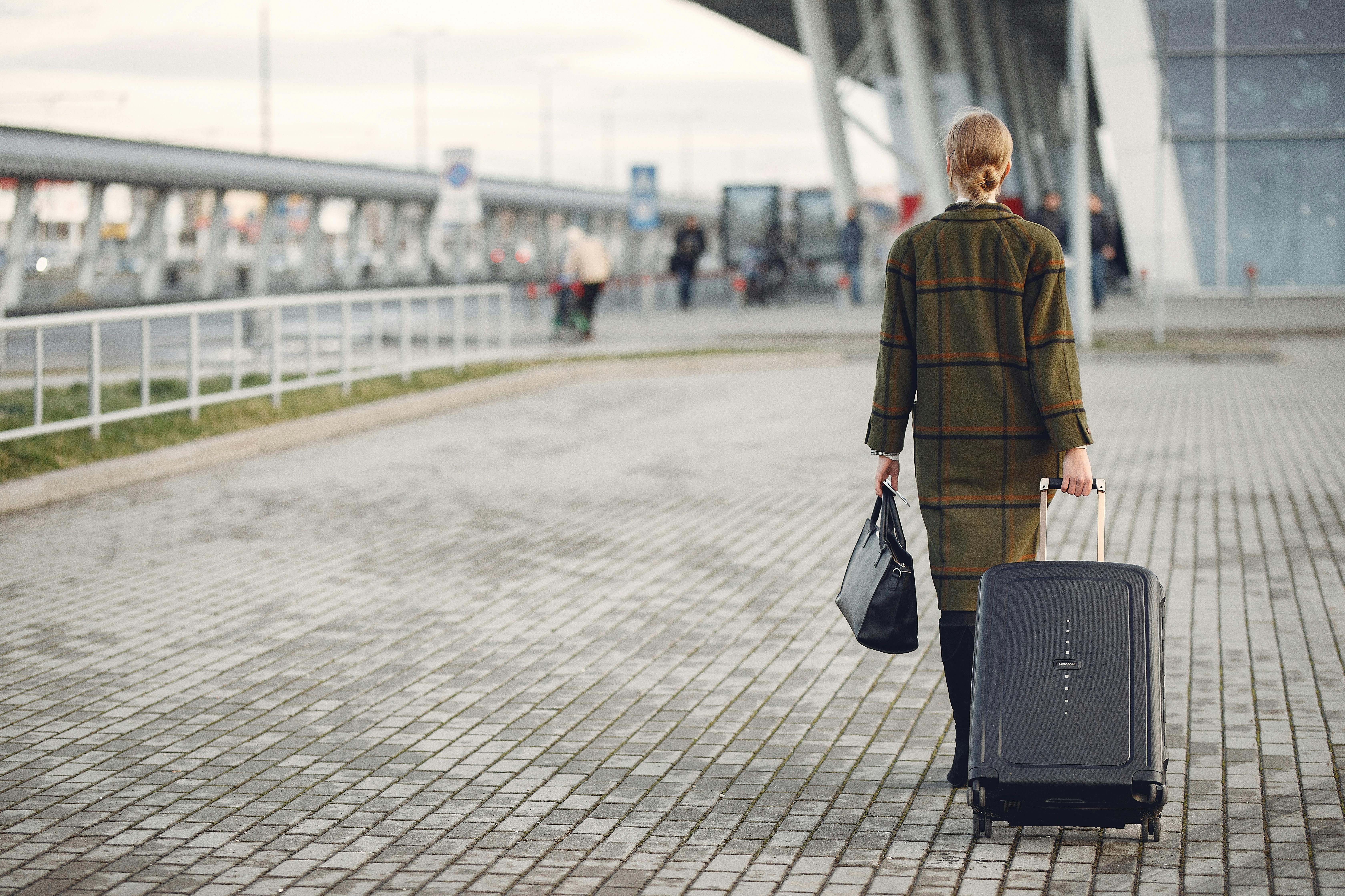 A woman walking away with her luggage | Source: Pexels