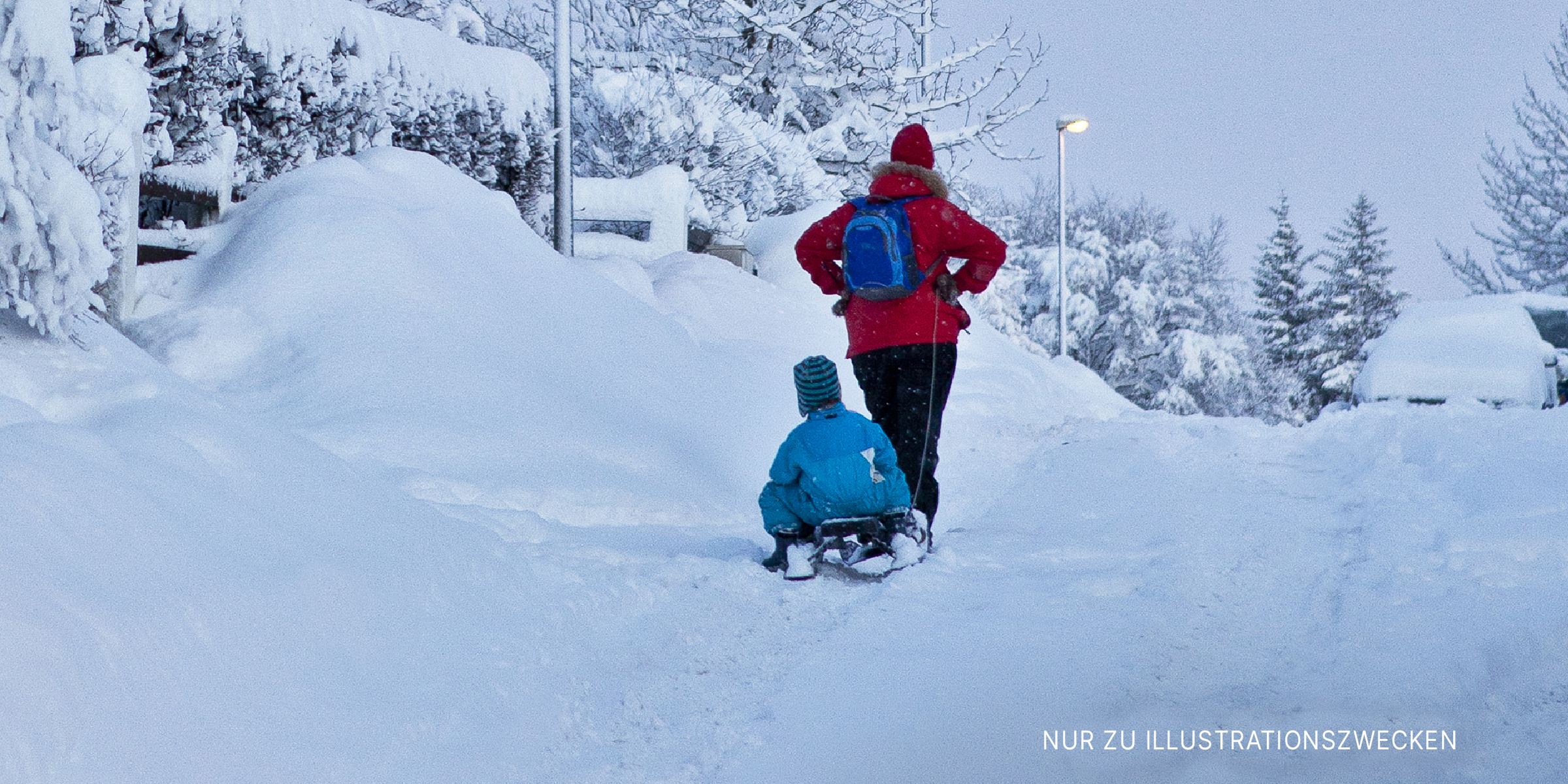 Ein Erwachsener transportiert ein Kind in einem Schlitten im Schnee | Quelle: Shutterstock