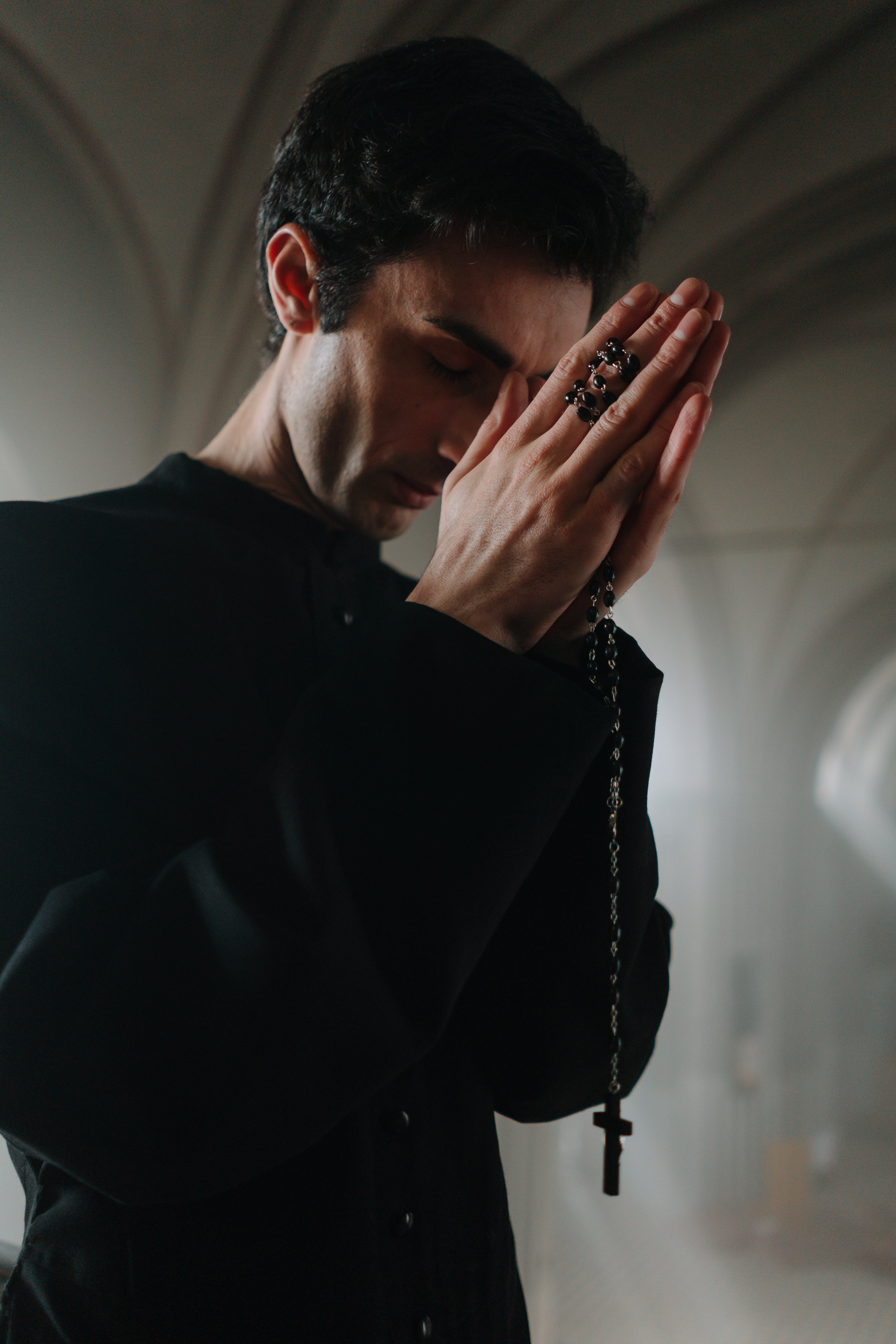 A man praying holding a rosary. | Source: Pexels