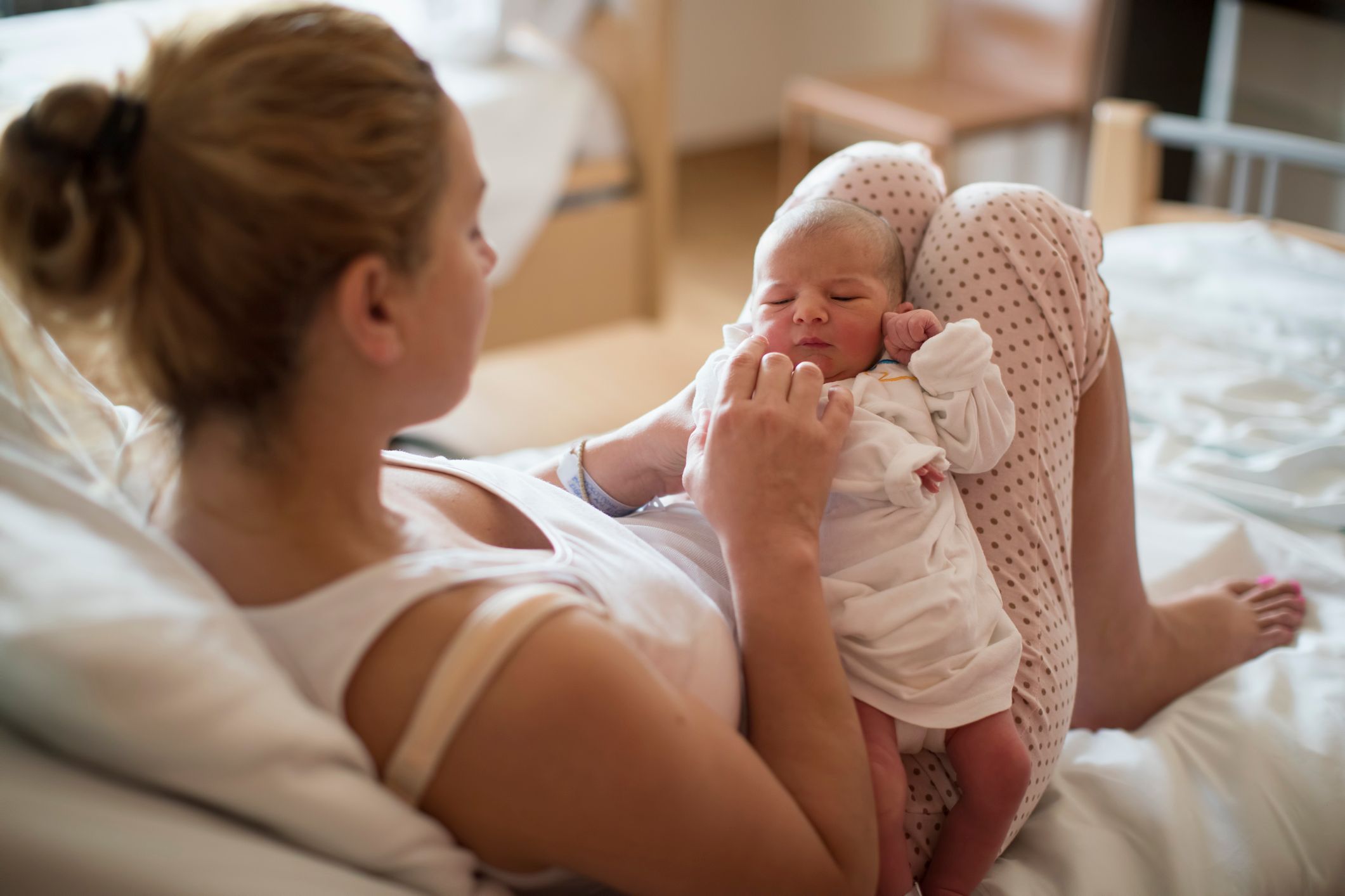 A mom holding her newborn baby in a hospital room. | Source: Shutterstock