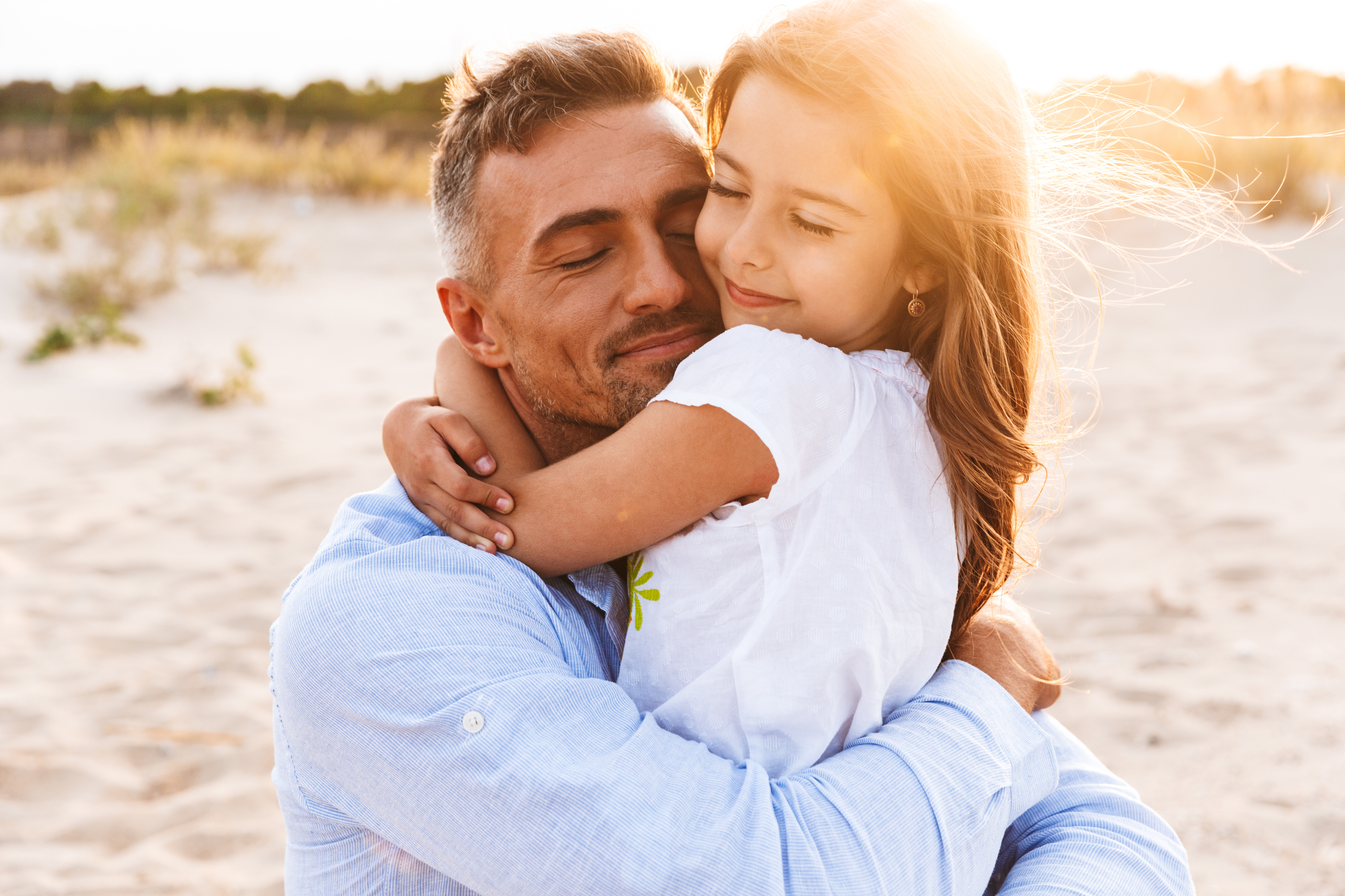 Happy father hugging his little daughter on the beach | Source: Shutterstock