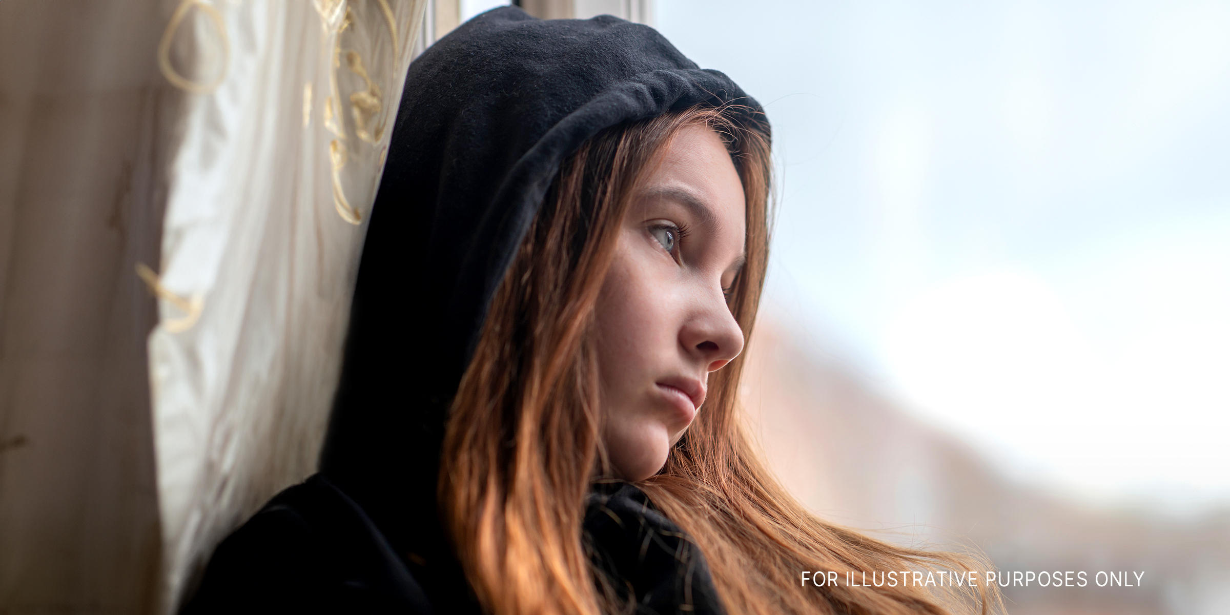 A sad teen girl looks out of the window | Source: Shutterstock
