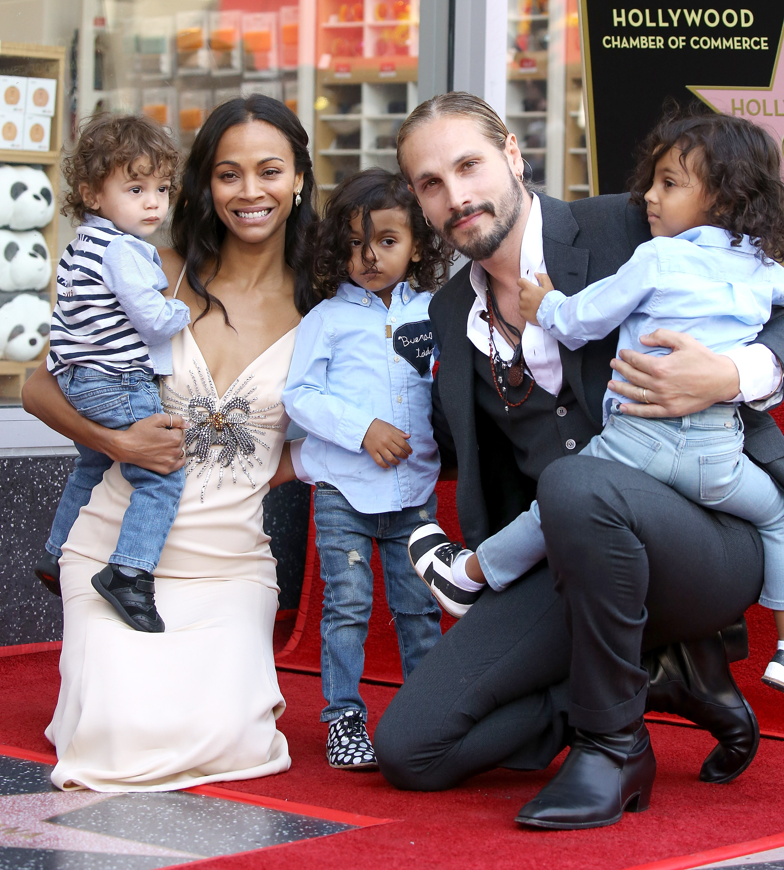 Zoe Saldaña and her husband, Marco Perego pose on their knees while they hold their sons, Cy, Bowie, and Zen Perego-Saldaña at The Hollywood Walk of Fame ceremony held in Hollywood, California on May 3, 2018.