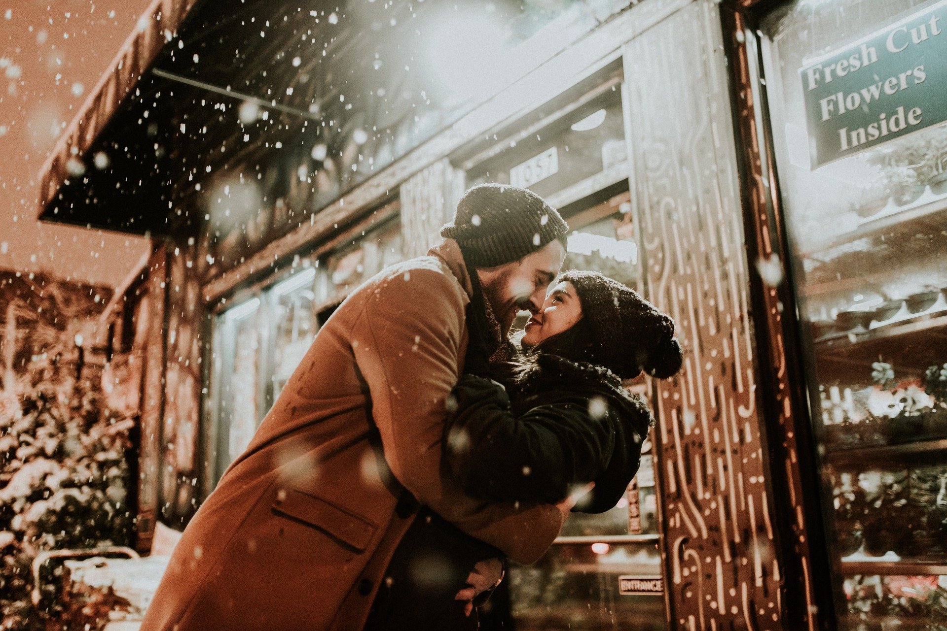 A couple embracing outside a flower shop while it snows | Photo: Pixabay/StockSnap
