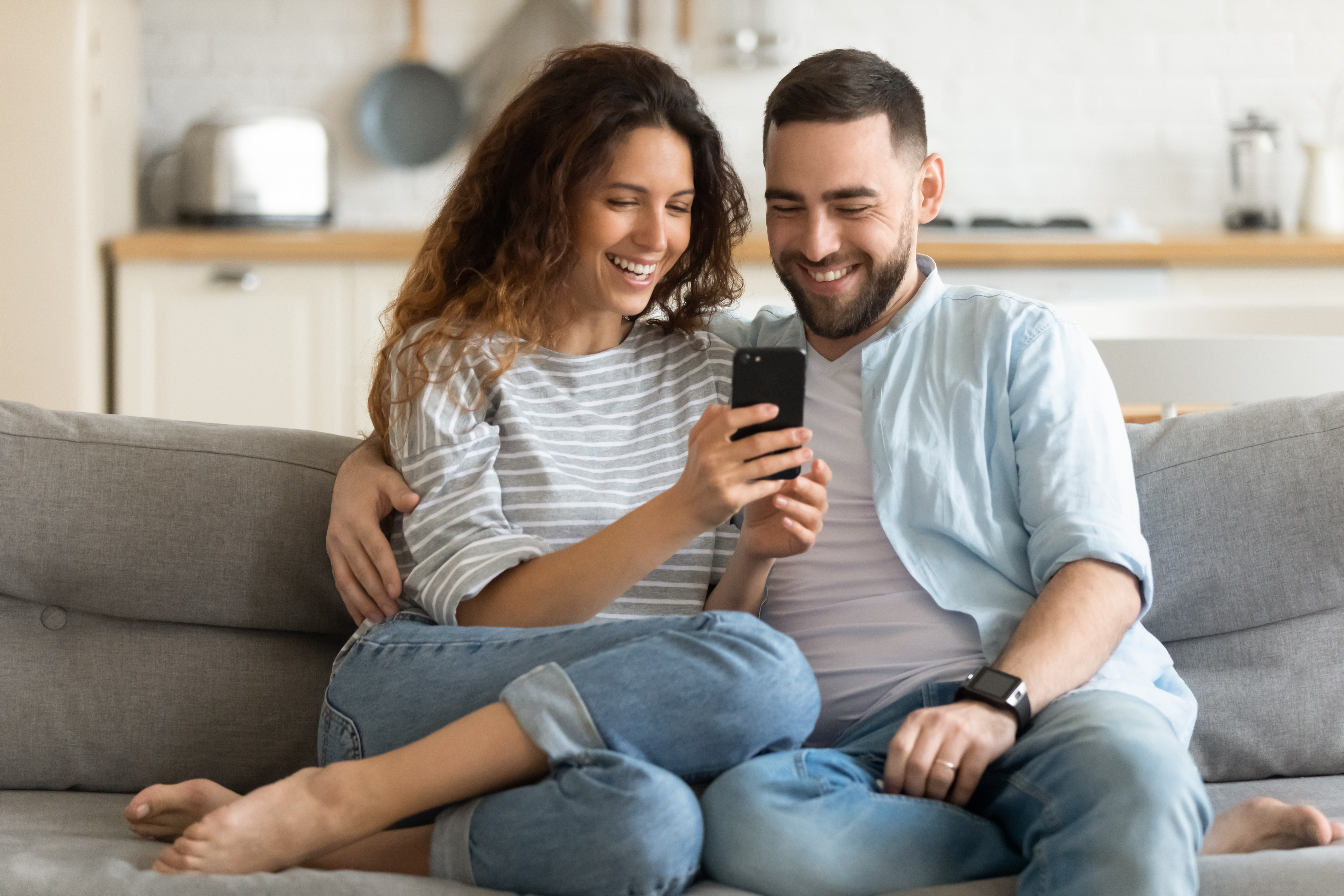 A couple using their smartphone while sitting on a couch | Source: Shutterstock