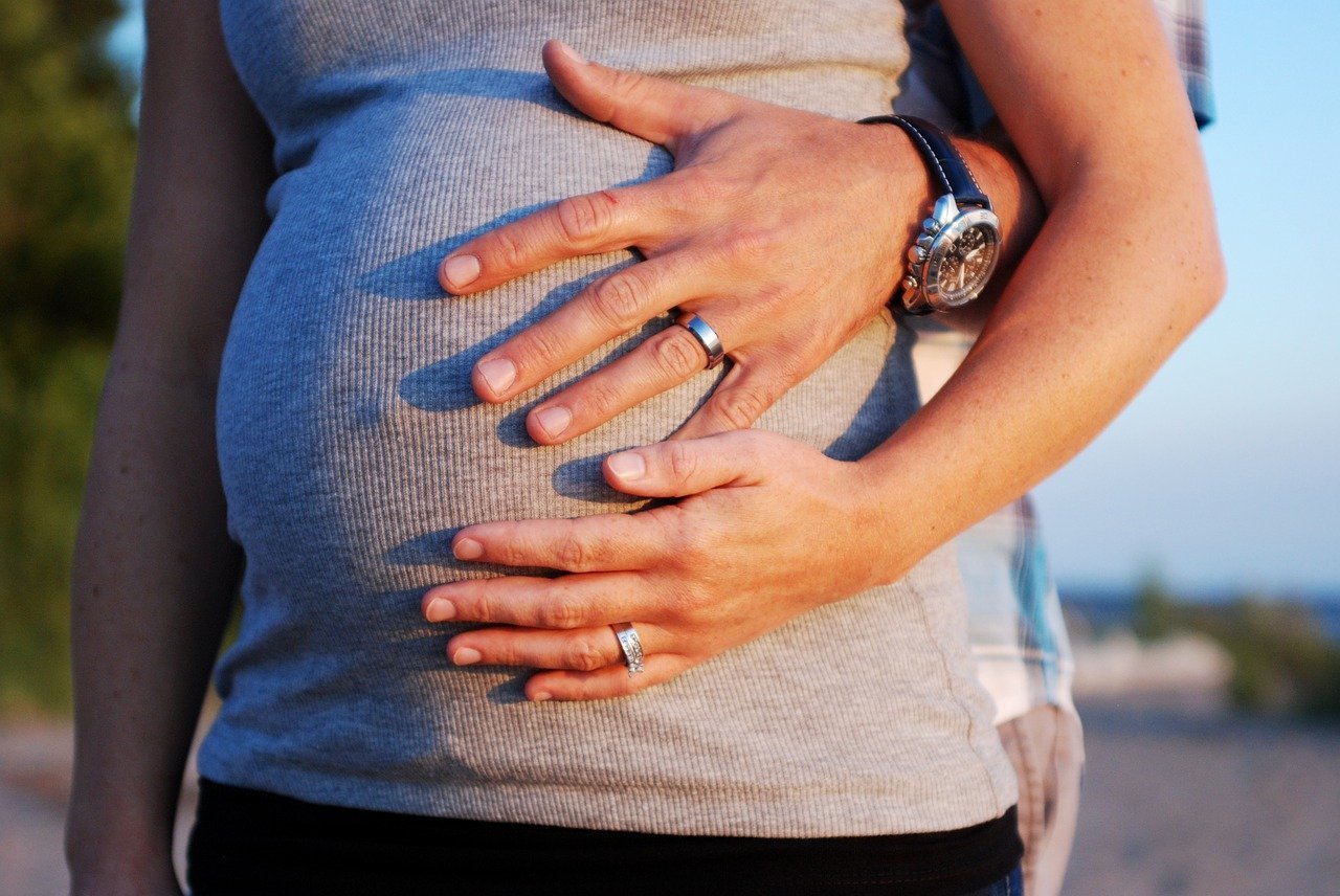 A man places a hand on a pregnant woman's baby bump. | Source: PixaBay