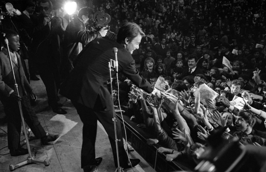 Le chanteur français Claude François chante sur la scène du Palais des Sports de Paris lors d'une matinée gratuite organisée pour 6000 enfants âgés de 8 à 13 ans le 21 novembre 1963, France. | Photo : Getty Images