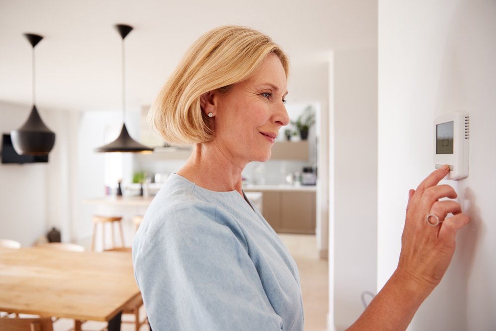 Mujer regulando la temperatura dentro de su hogar. | Foto: Shutterstock