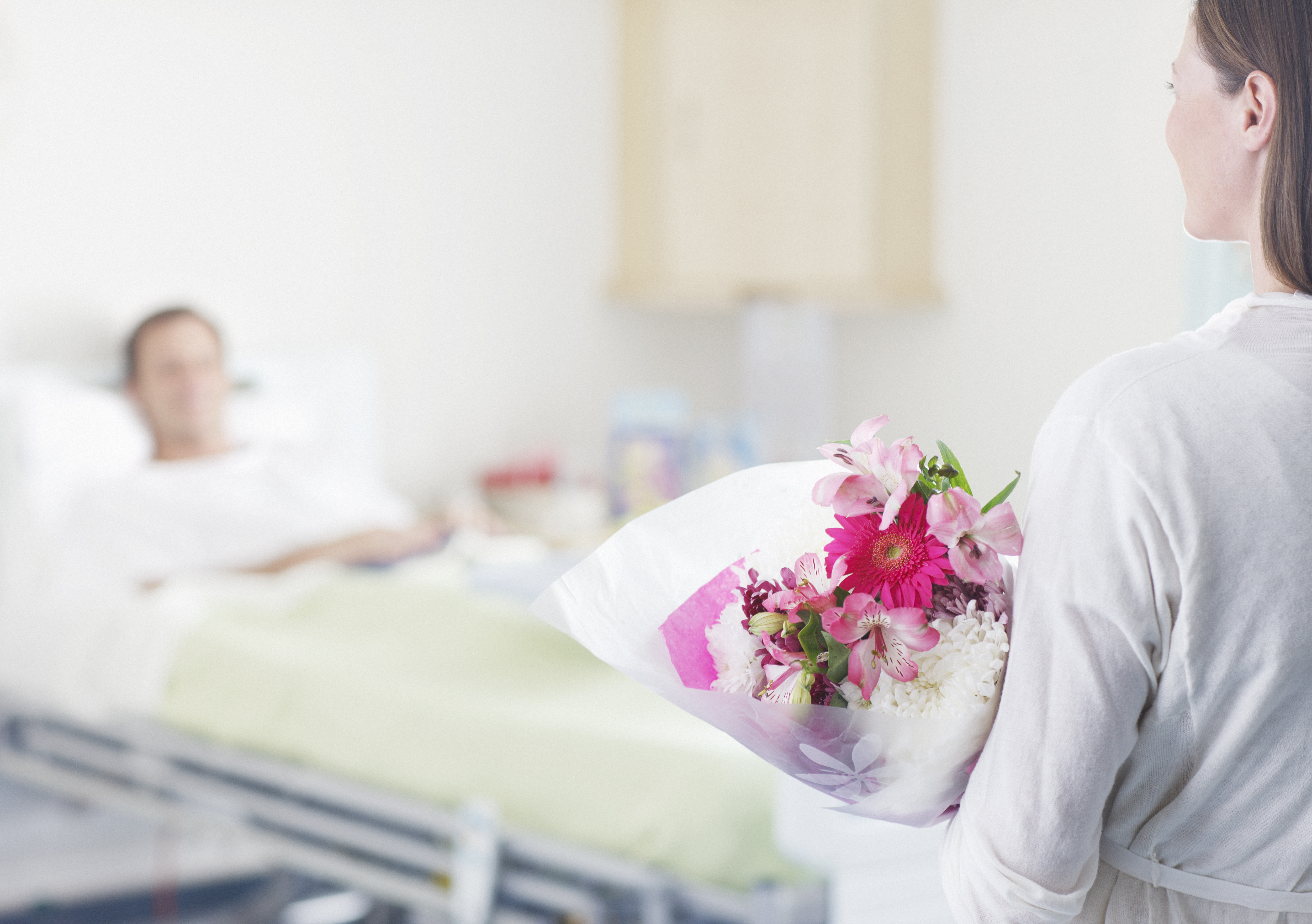 A woman bringing flowers to a man in a hospital | Source: Getty Images