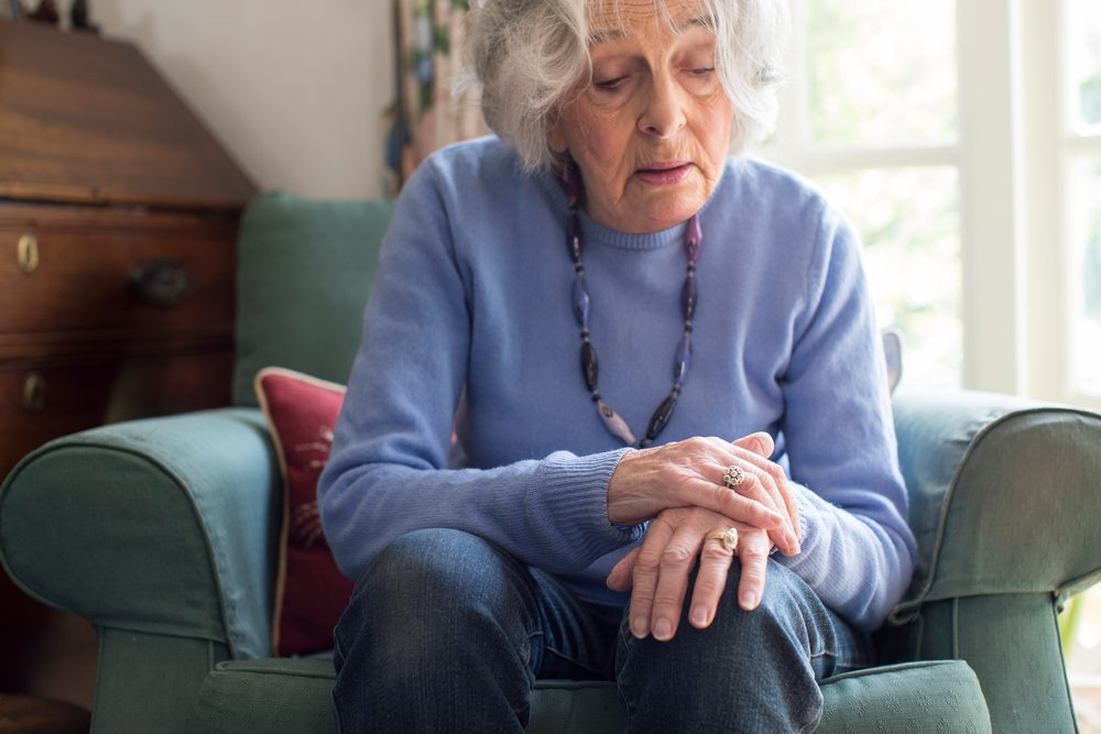 Anciana mirando hacia abajo sentada en un sofá. | Foto: Shutterstock
