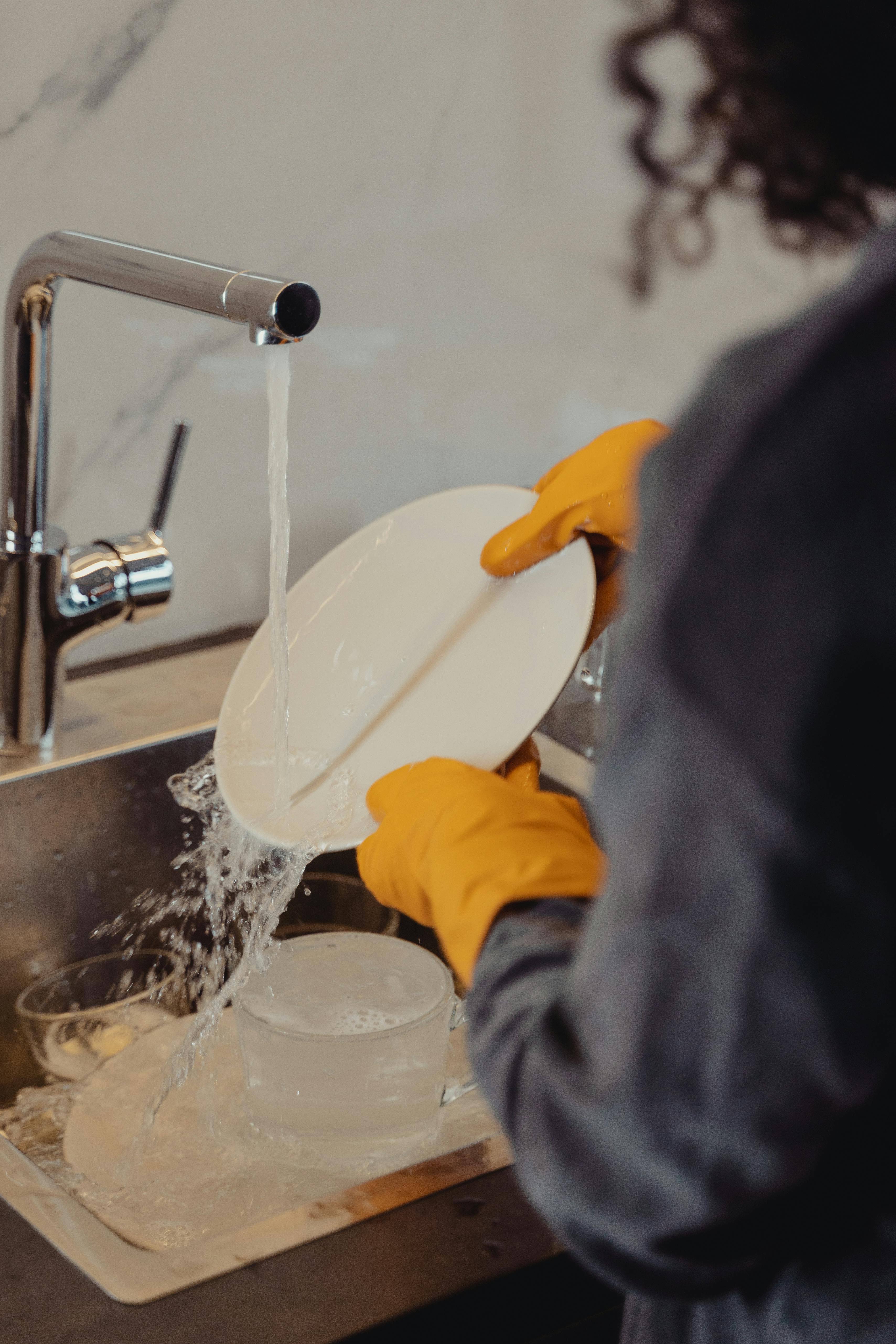 A woman rinsing dishes | Source: Pexels