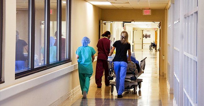 Three nurses wheel a patient lying a bed down a hospital corridor towards an exit sign | Source: Shutter Stock