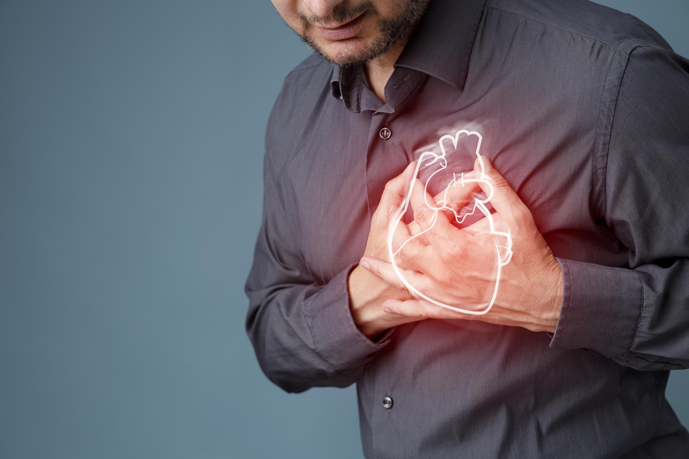 Young man clutching his chest, potentially experiencing cardiac pain or severe discomfort | Source: Getty Images