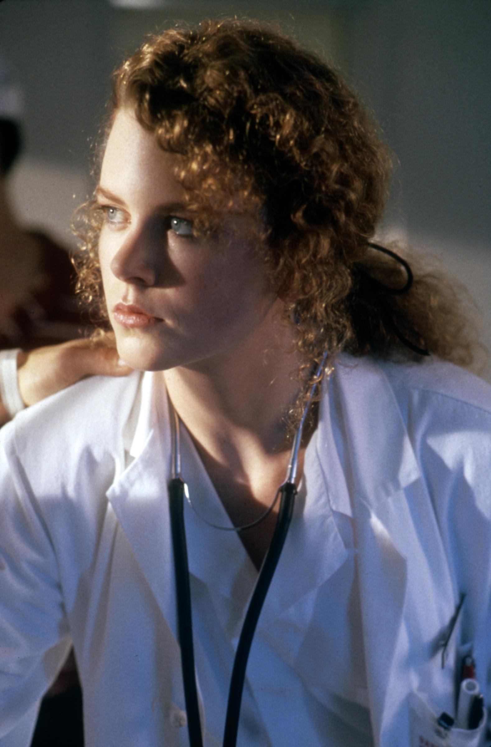 Nicole Kidman with tightly coiled red curls pulled back into a low ponytail on the set of "Days of Thunder." Her natural texture is fully visible, with soft ringlets framing her face.