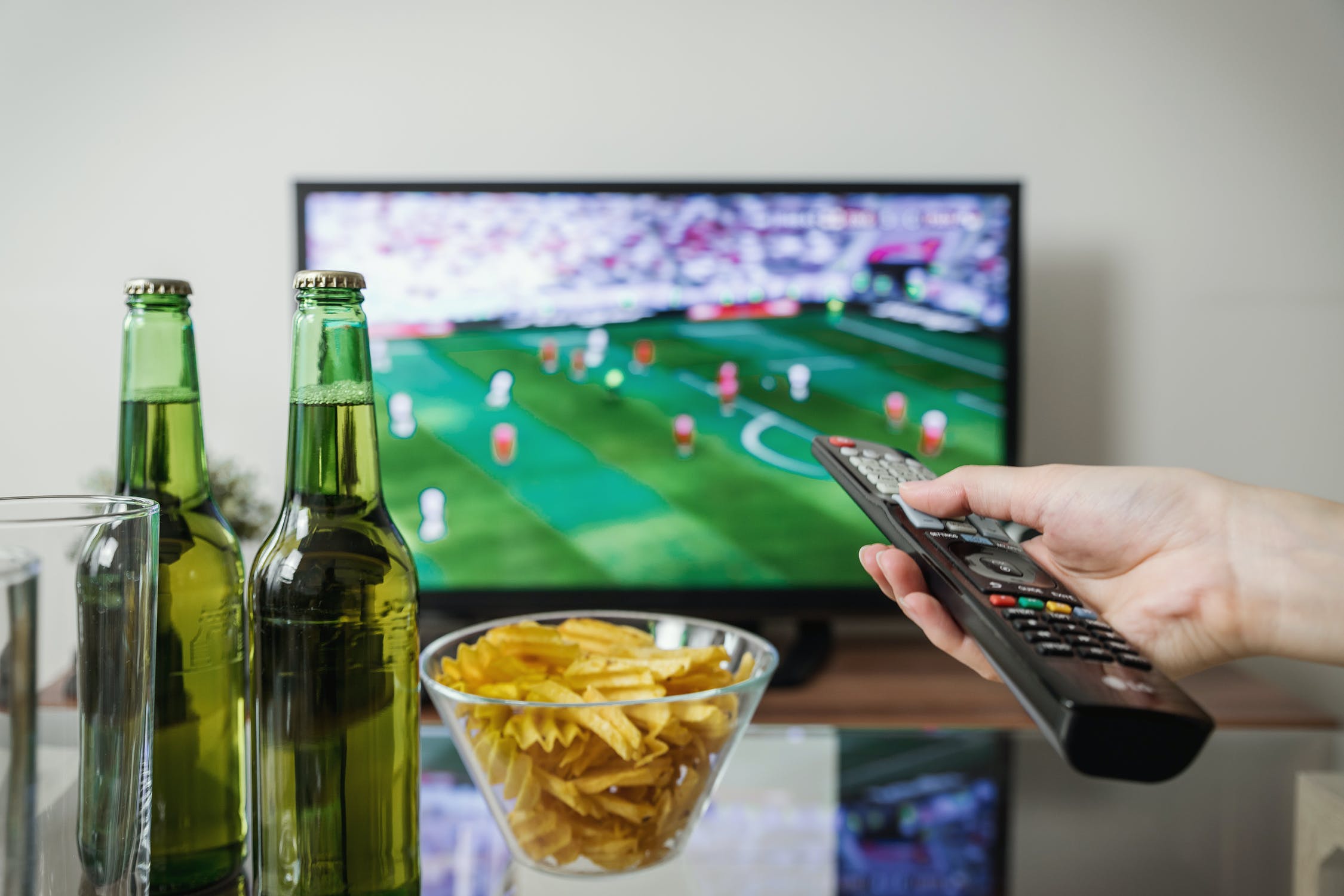 Persona disfrutando de la tele y algunos bocadillos y bebidas. | Foto: Shutterstock